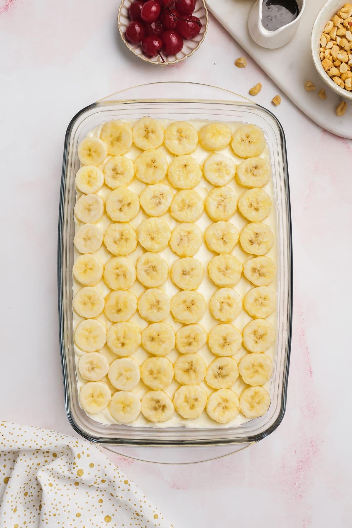 sliced bananas laid out in rows on the cream cheese layer