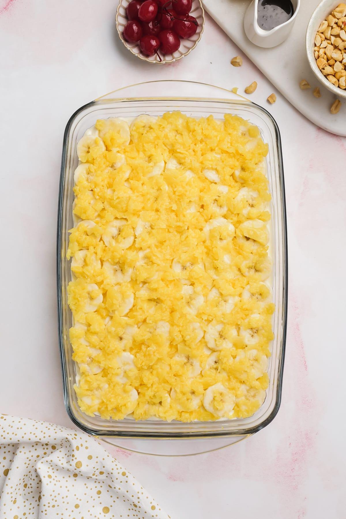 sliced pineapple rounds laid on top of banana slices all over the cake