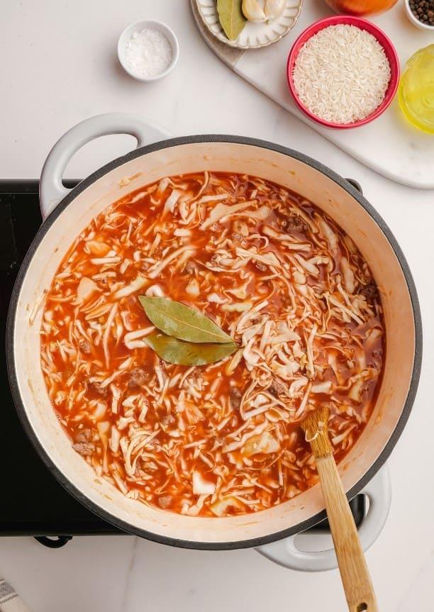 cabbage roll soup ingredients in pot with wooden spoon