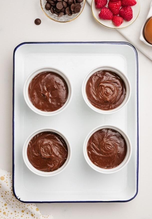 unbaked molten lava cakes in ramekins on baking sheet