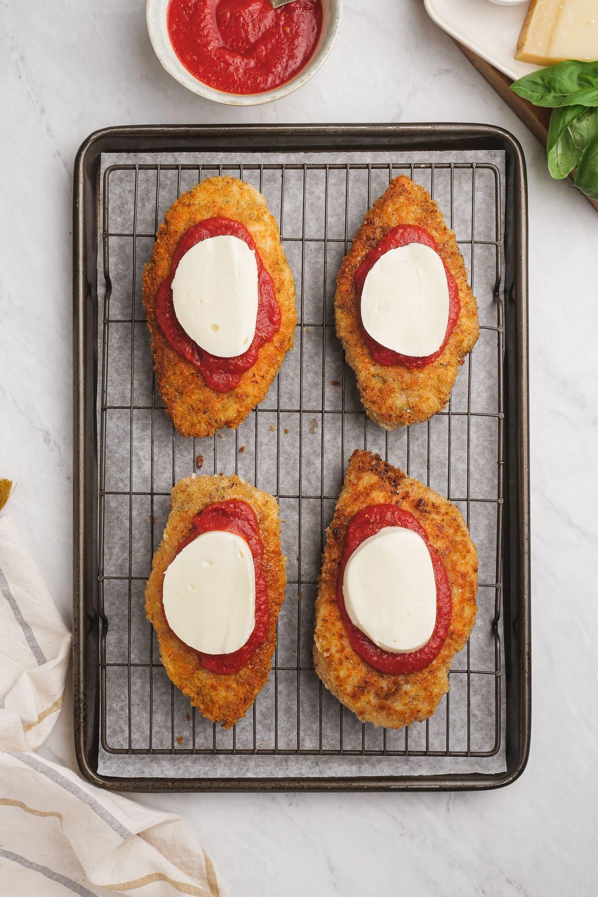 breaded chicken breast with marinara sauce and a slice of mozzarella cheese on each one