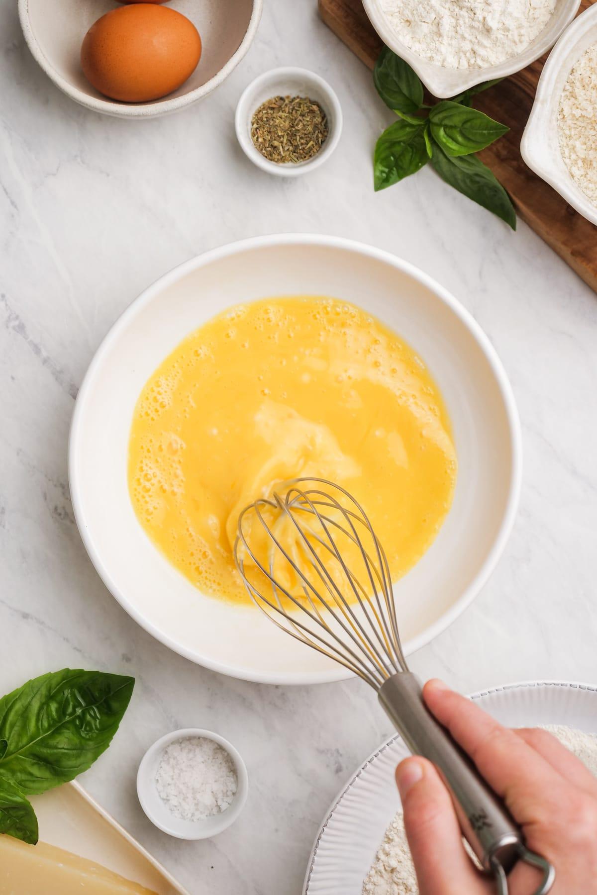 beaten eggs in a bowl with a whisk