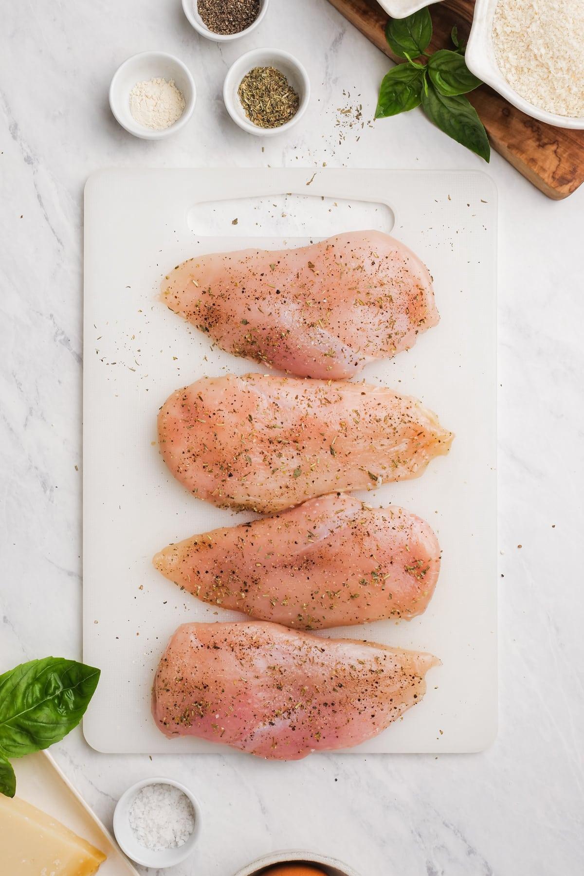 chicken breasts seasoned and on a cutting board