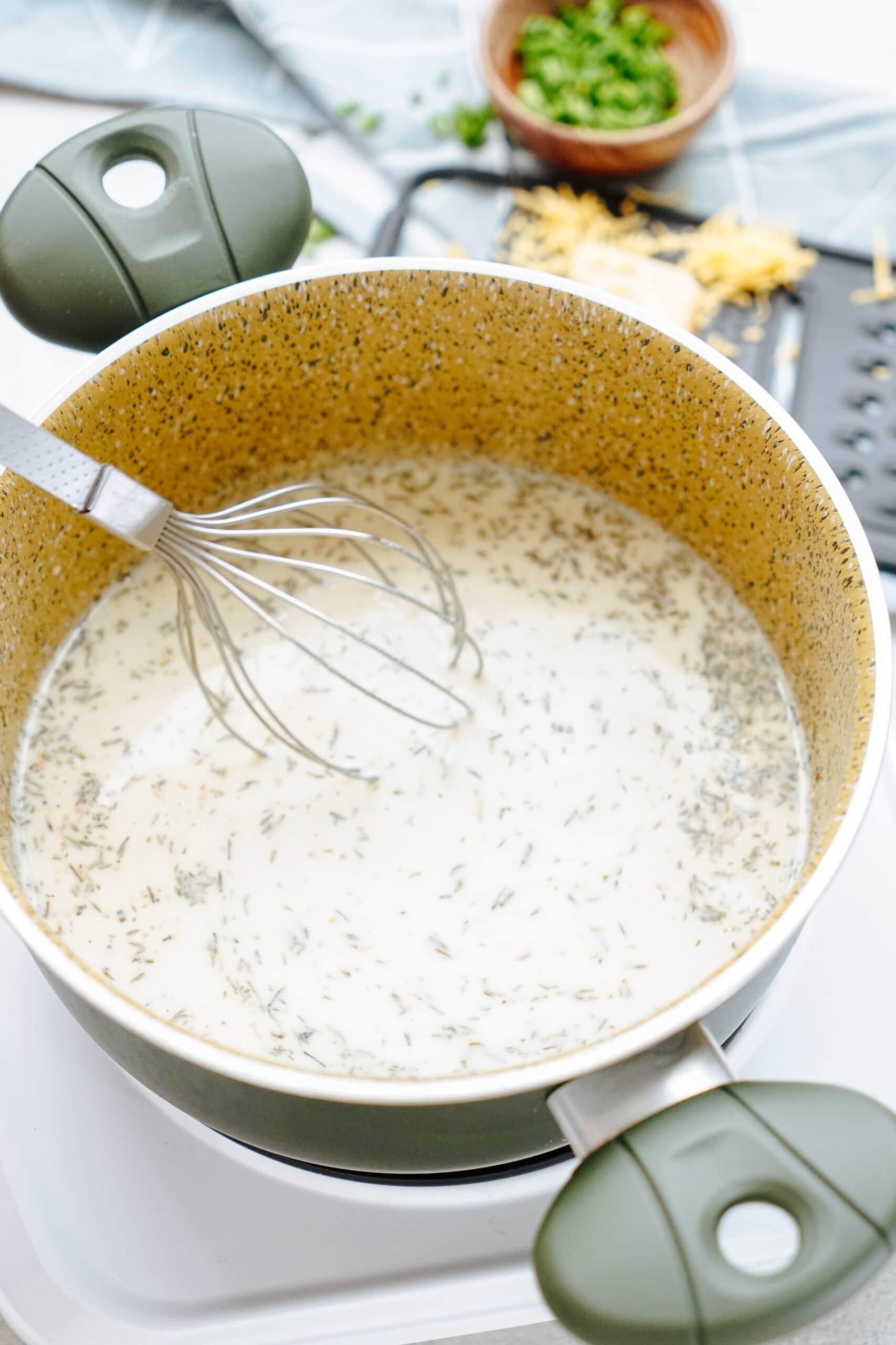 homemade cream of chicken soup in a saucepan with a whisk