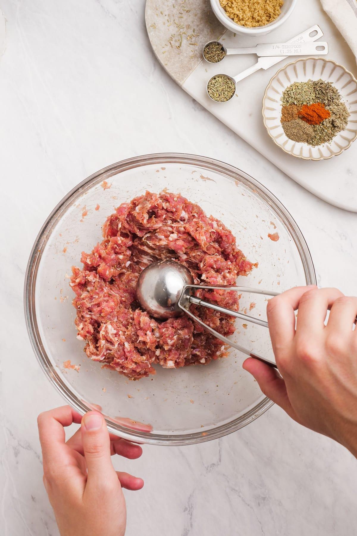 using a cookie scoop to scoop sausage mixture into balls