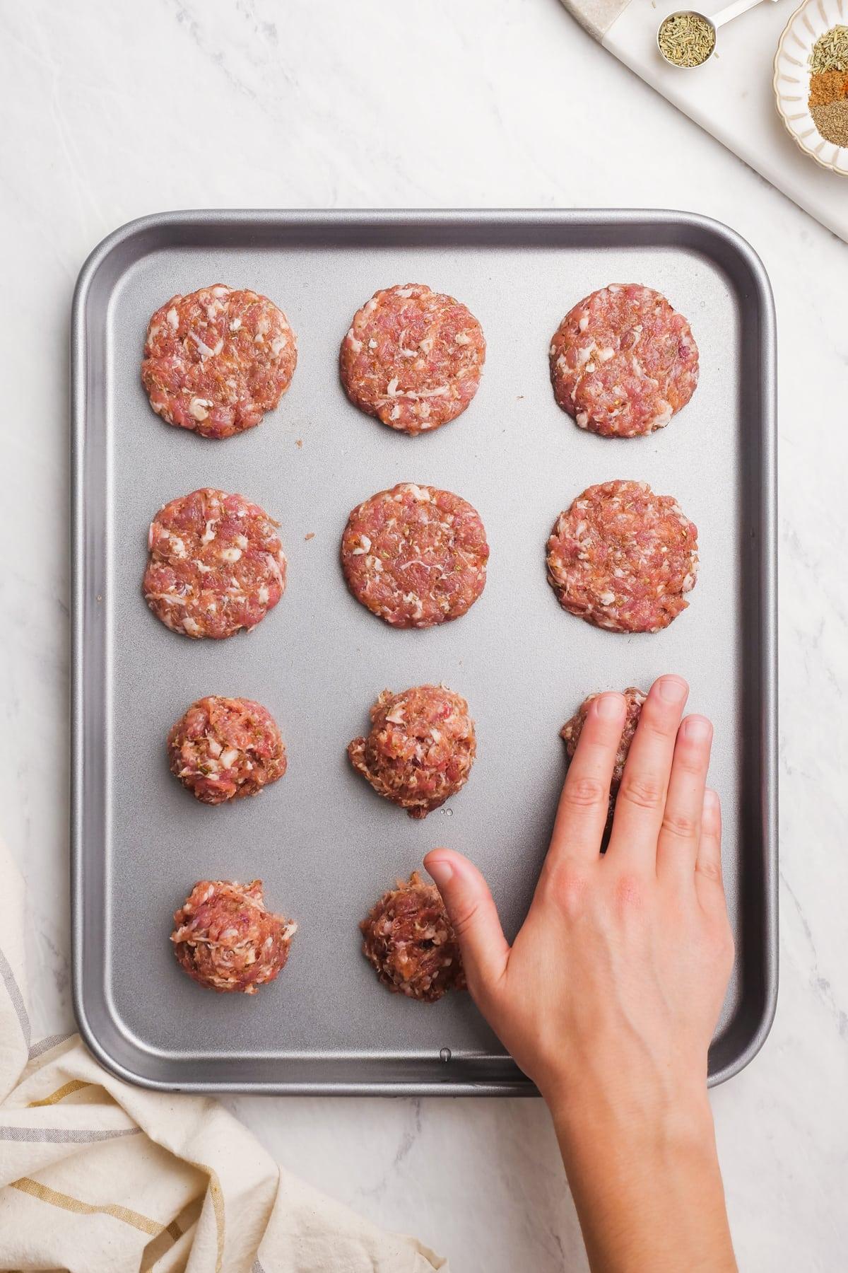 raw sausage balls being flattened on baking sheet