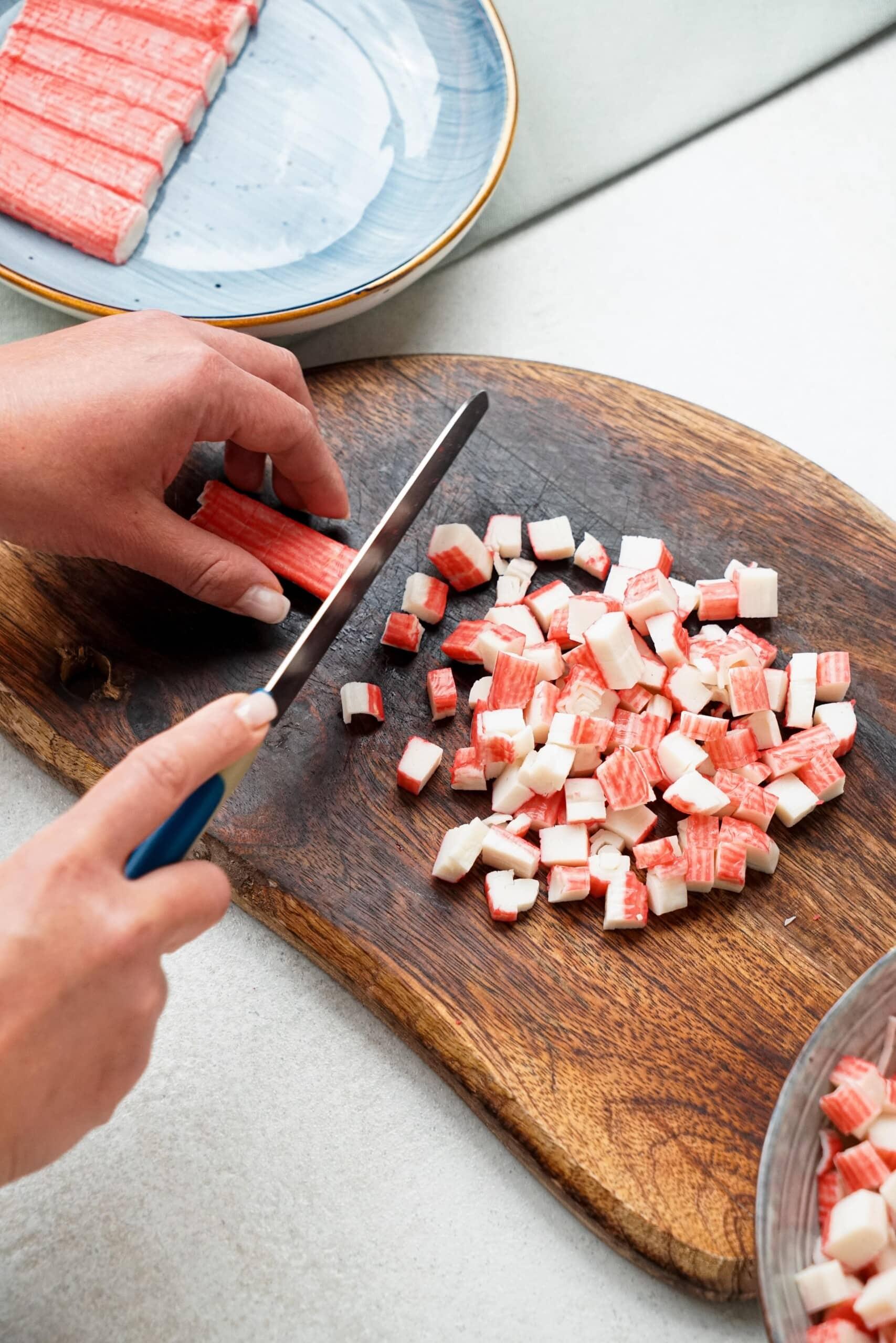 woman's hands chopping crab meat on a cutting board