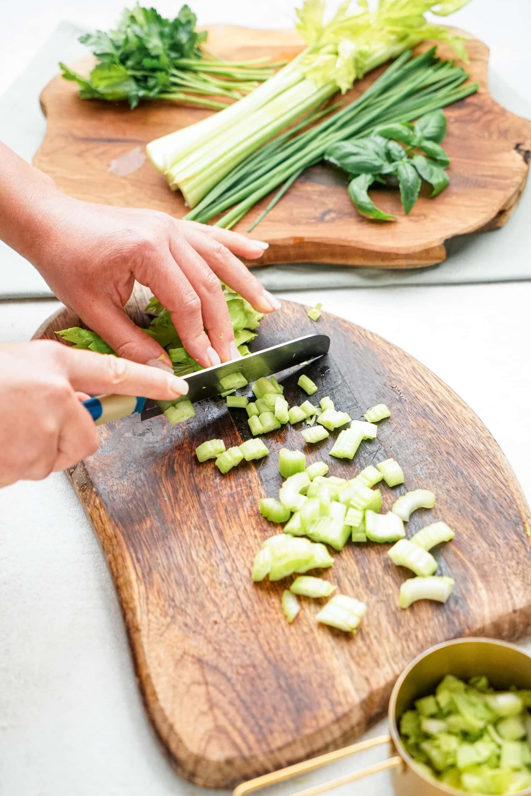 woman's hands chopping celery on cutting board