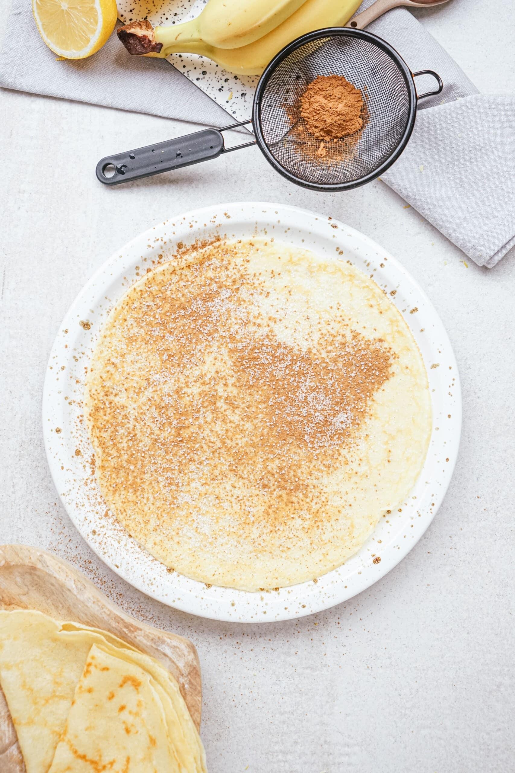 cinnamon sugar sprinkled onto a crepe