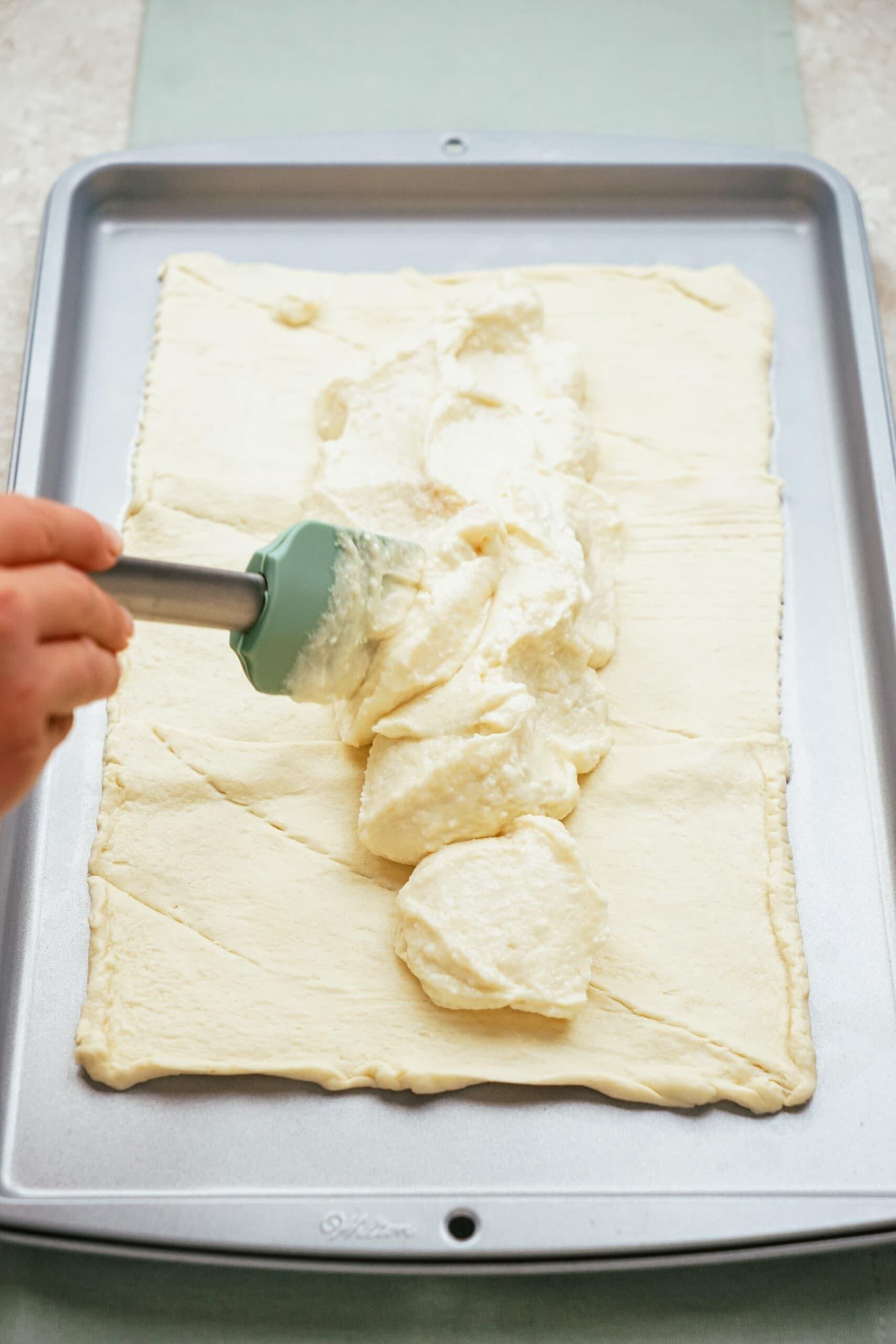 cream cheese filling being spread down the center of crescent dough