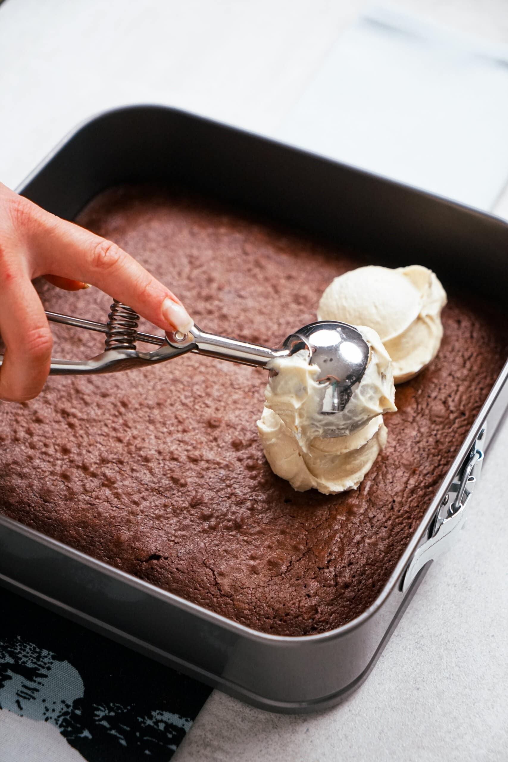 woman's hand adding frosting with a scoop