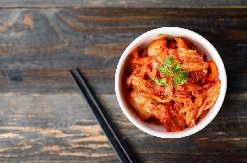 Kimchi in a bowl next to chopsticks