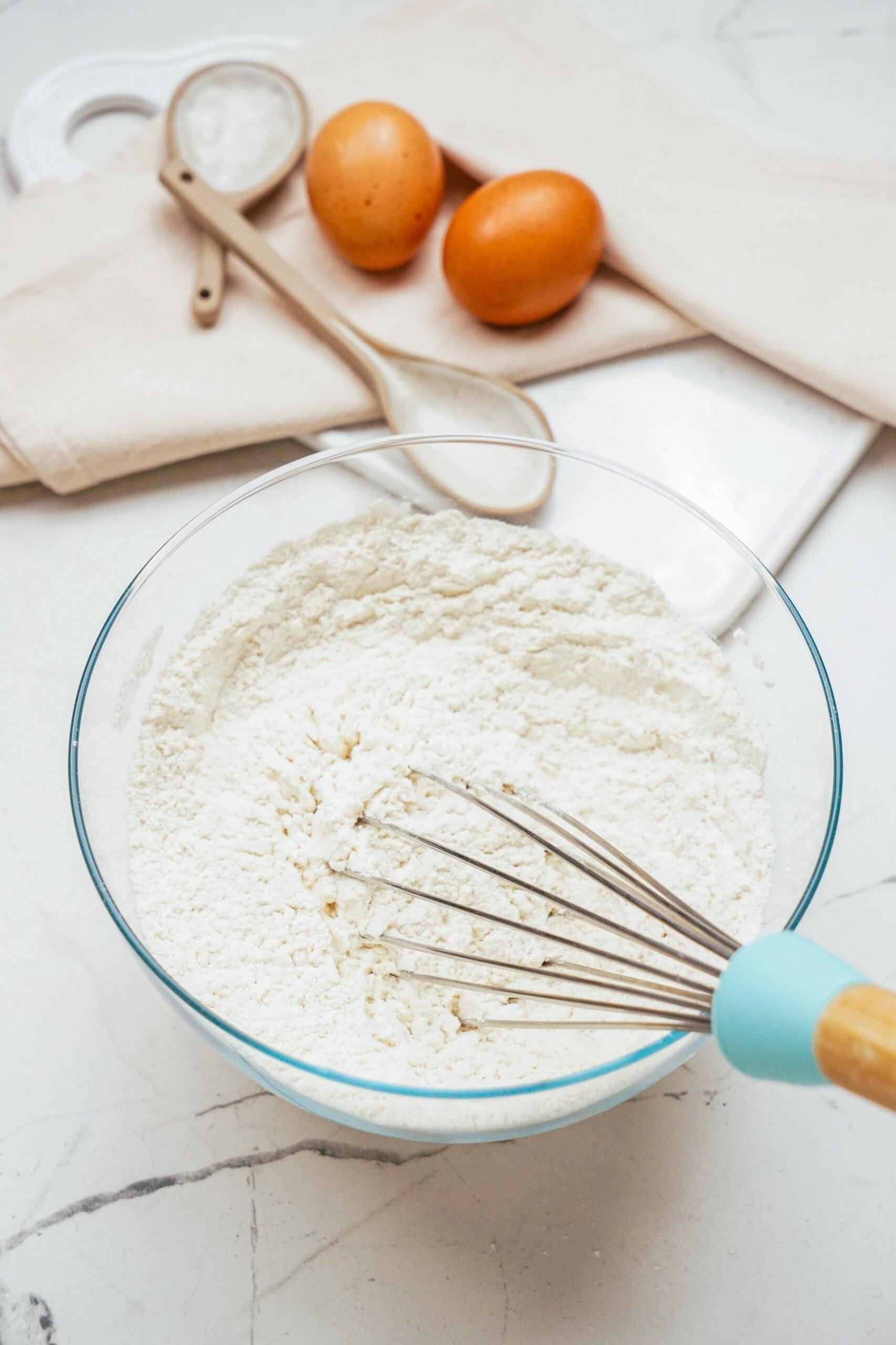 whisking dry cake ingredients in glass bowl