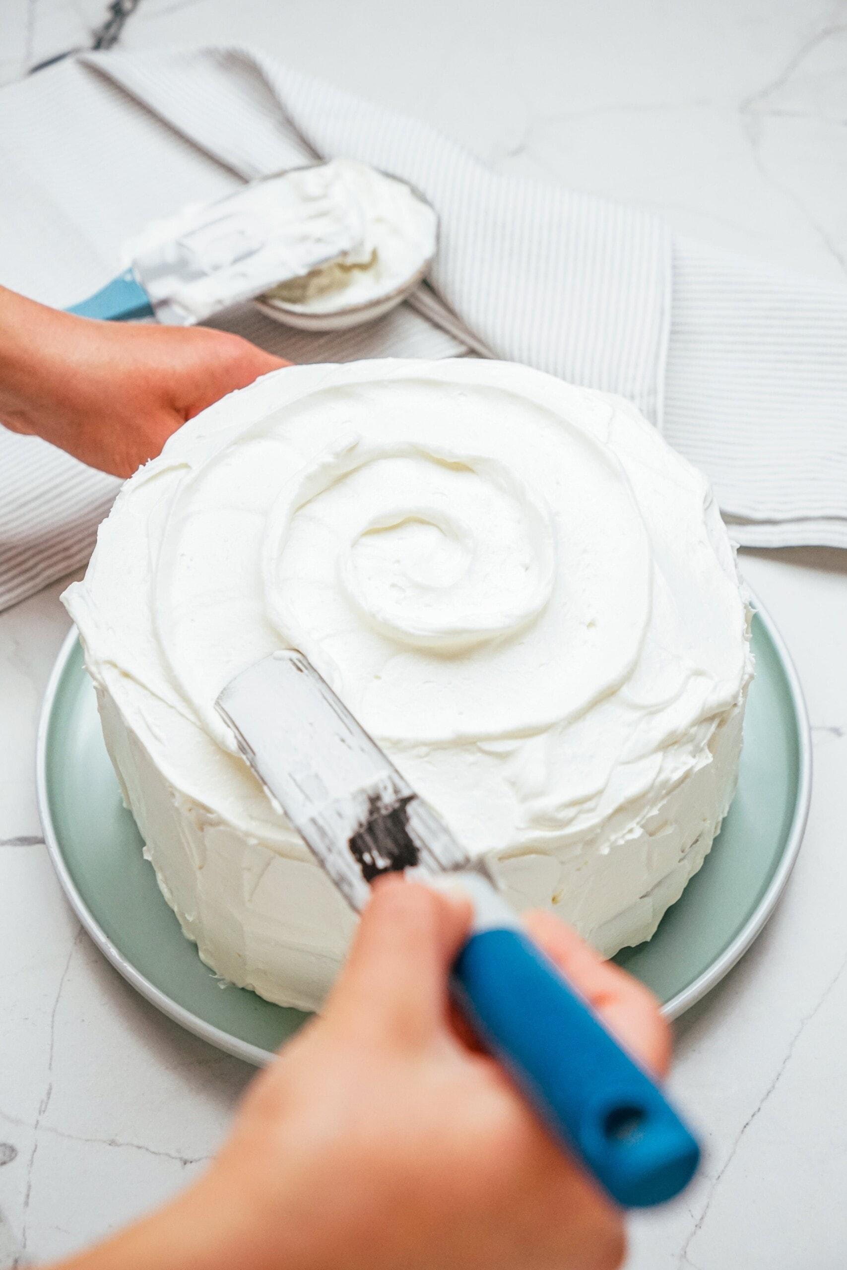 woman's hand frosting cake