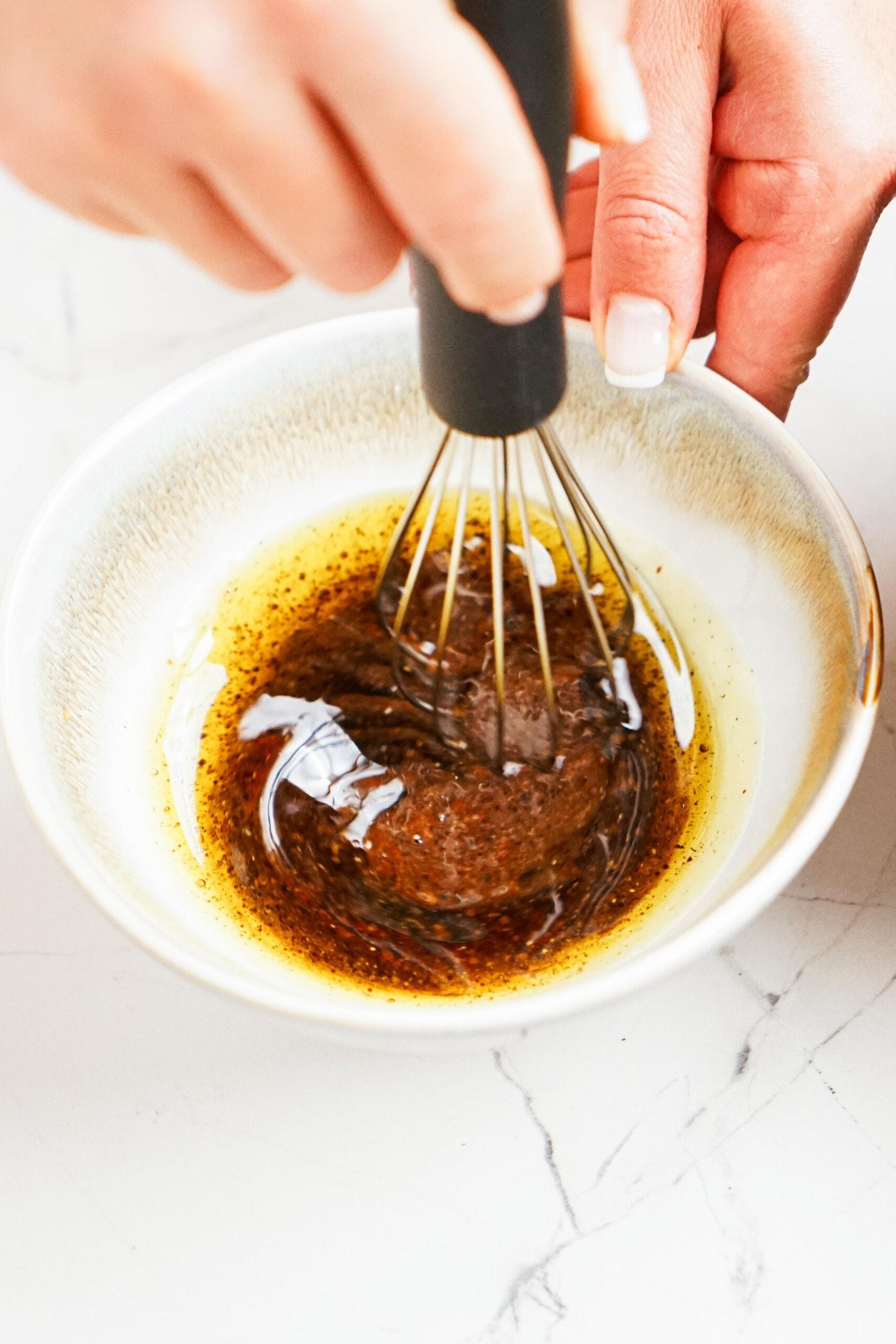 whisking balsamic dressing ingredients together in a bowl