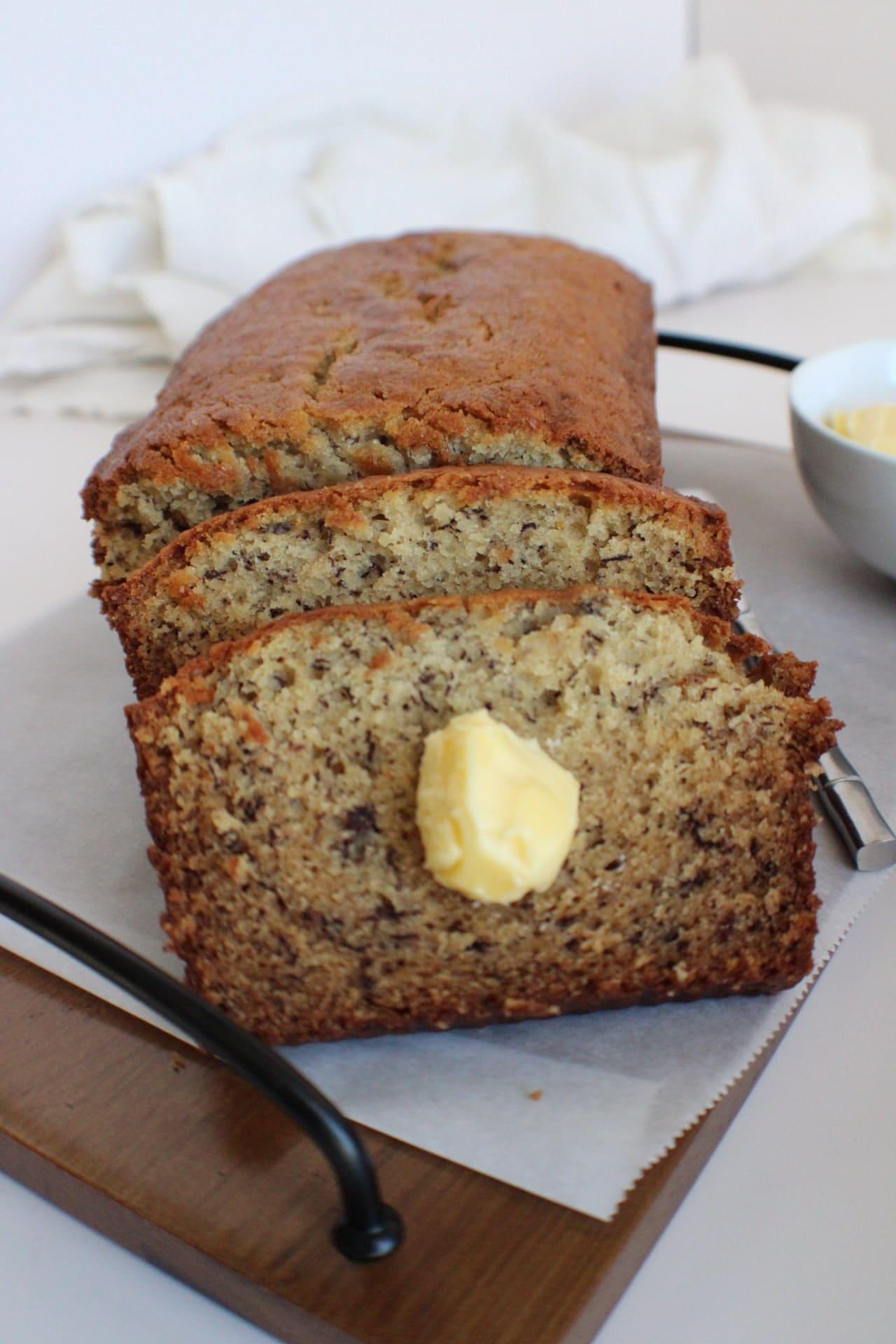 sliced banana bread on a cutting board with butter on a slice