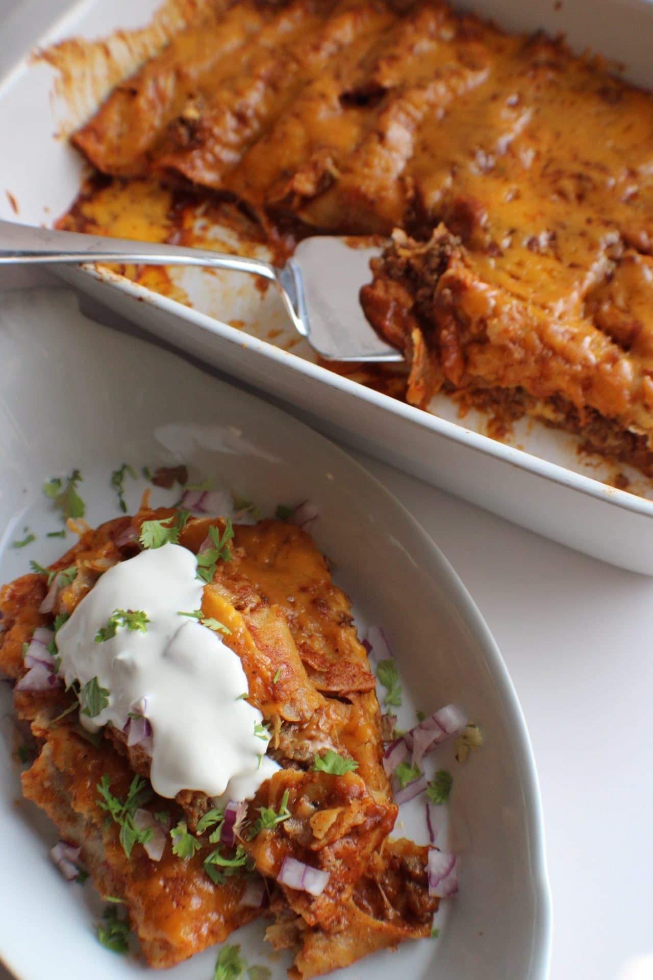 chorizo enchiladas on a plate next to the pan of enchiladas