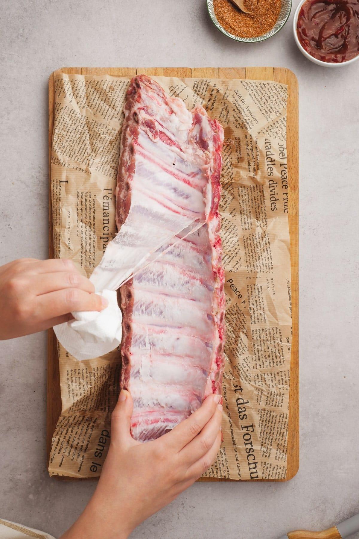woman's hand pulling silver skin off ribs