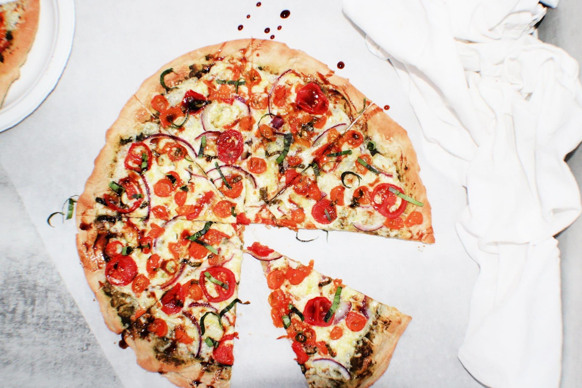 Bruschetta Pizza on a table with a couple pieces gone