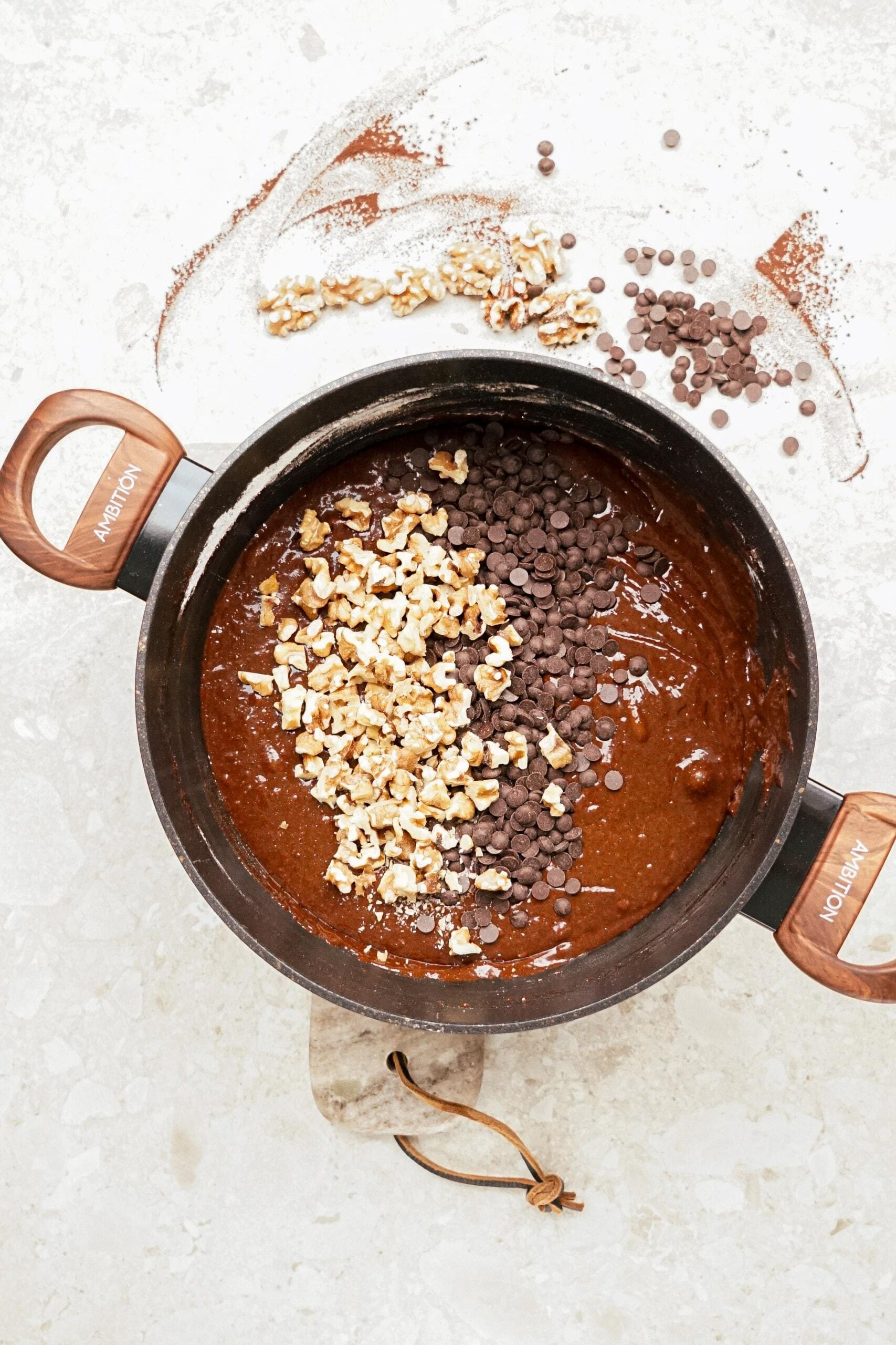 adding chocolate chips and walnuts to brownie mixture