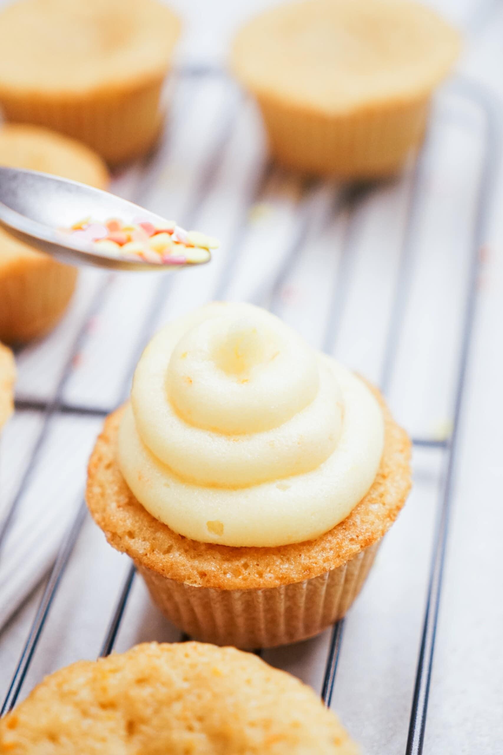 adding sprinkles to frosted cupcake