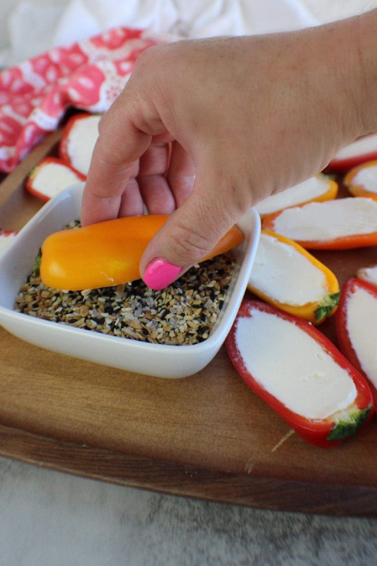 woman's hand pressing a pepper face down into seasoning