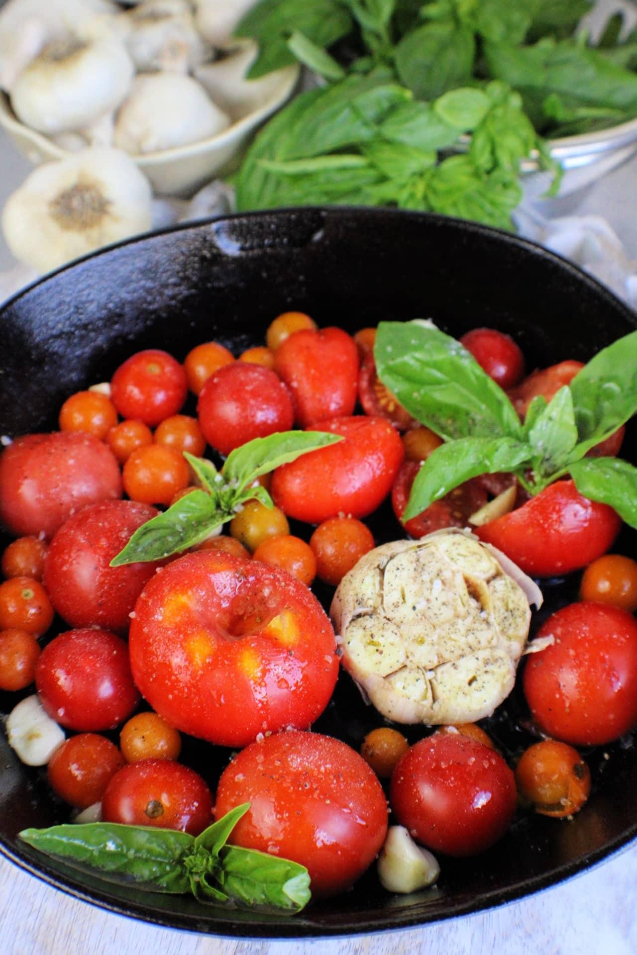 fresh tomatoes in a cast iron skillet with garlic bulb