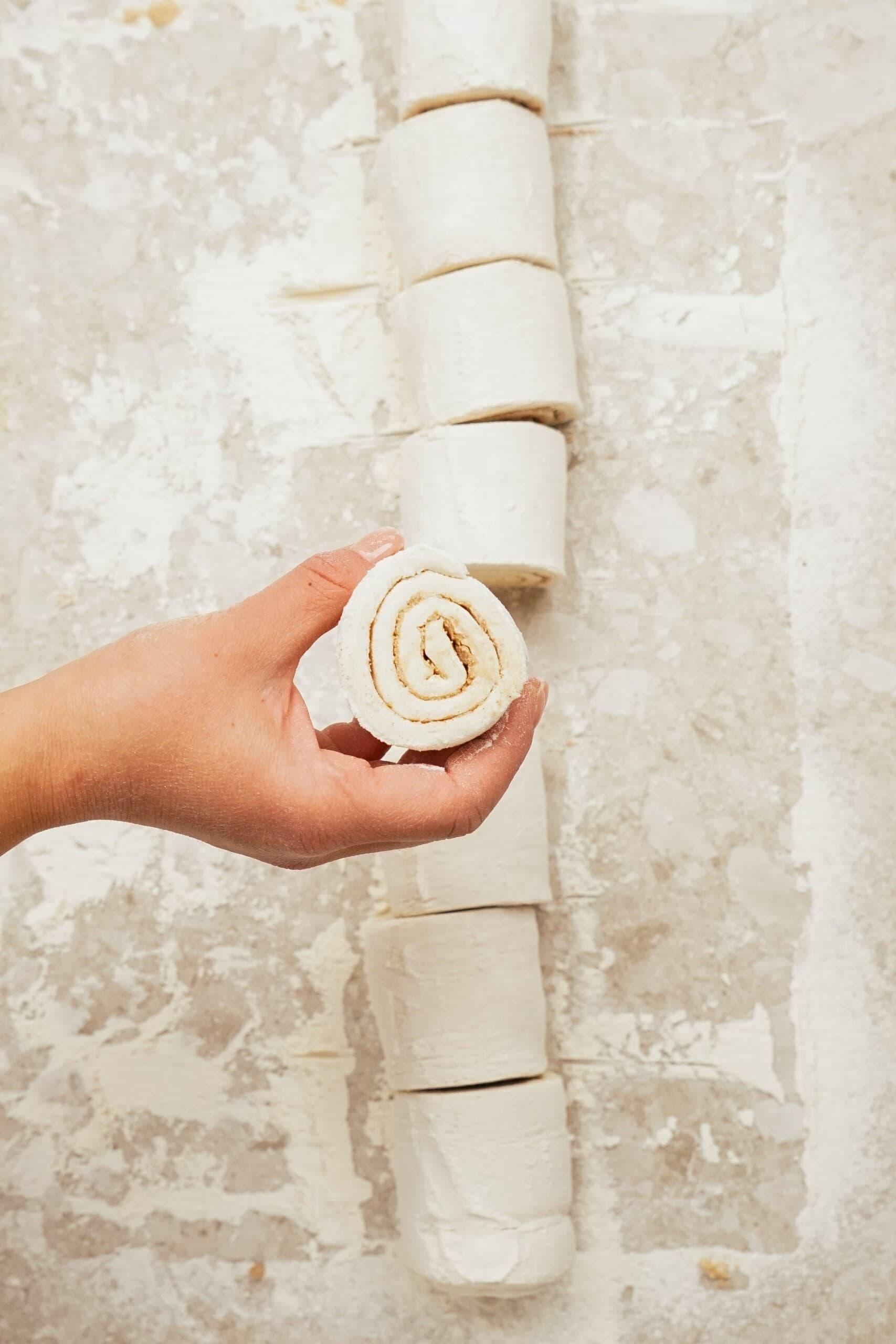 Woman's hand holding up on piece of Puff Pastry sheet from the cut up roll