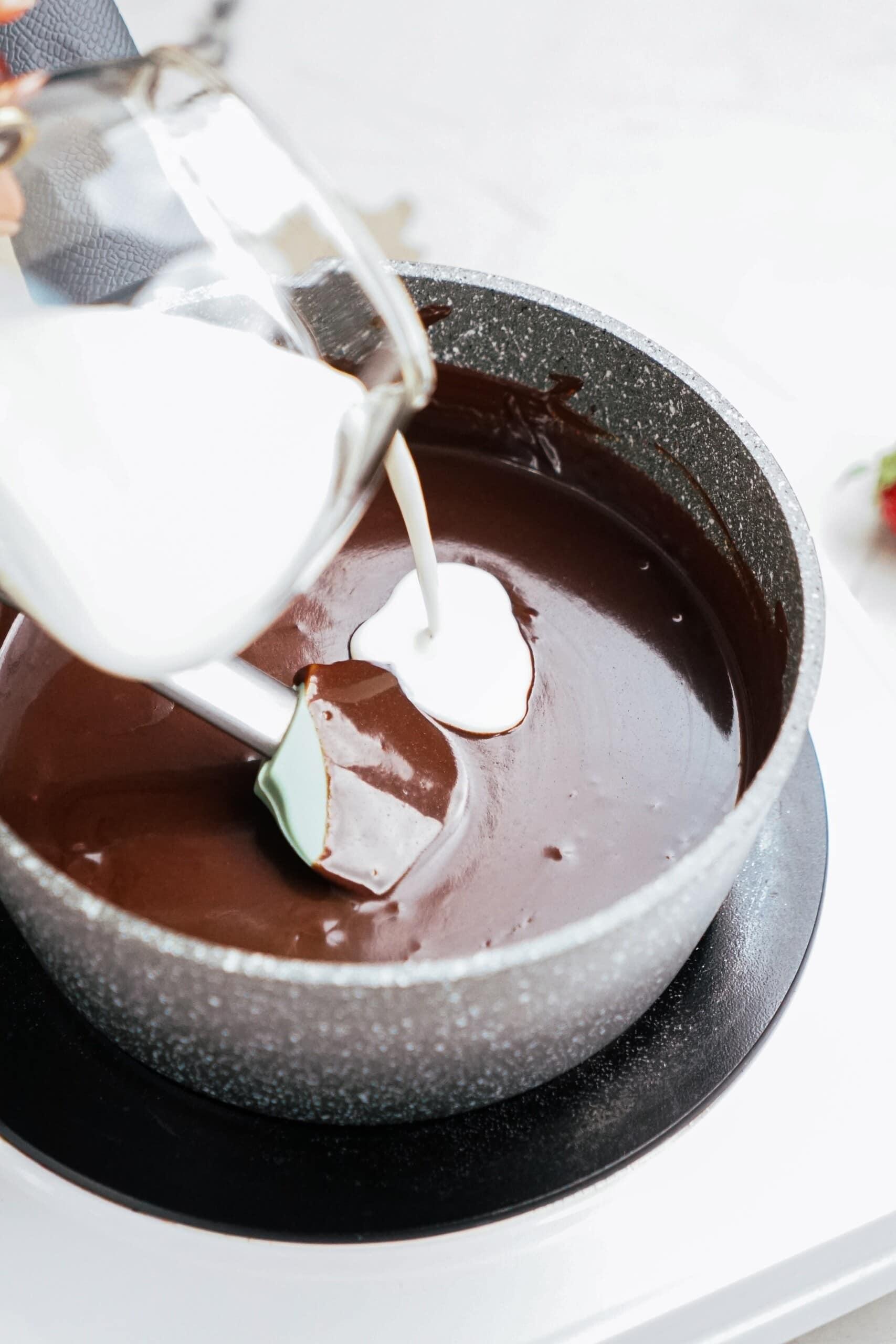 milk pouring into dipping chocolate in sauce pot