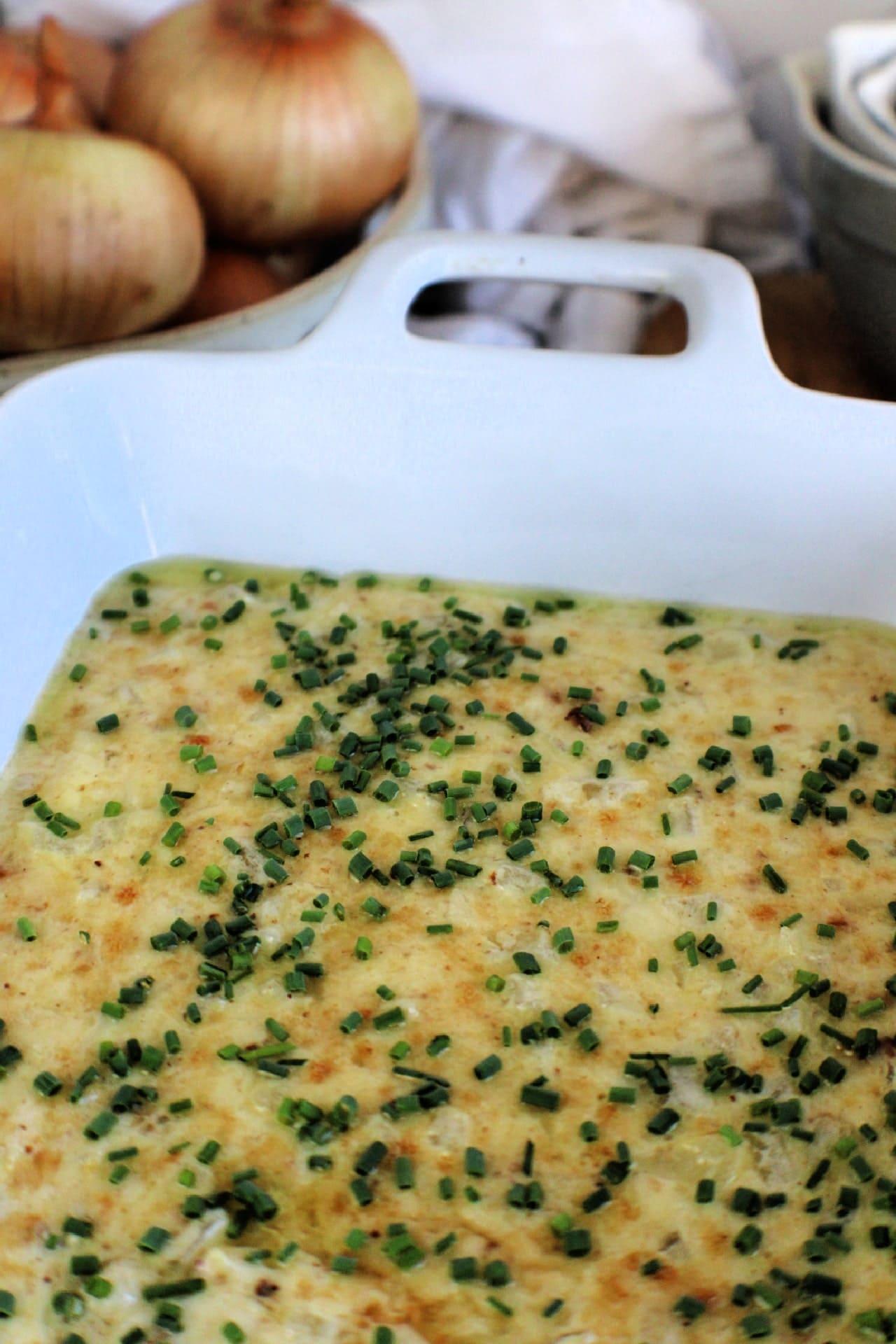 close up of baked hot onion dip in baking dish