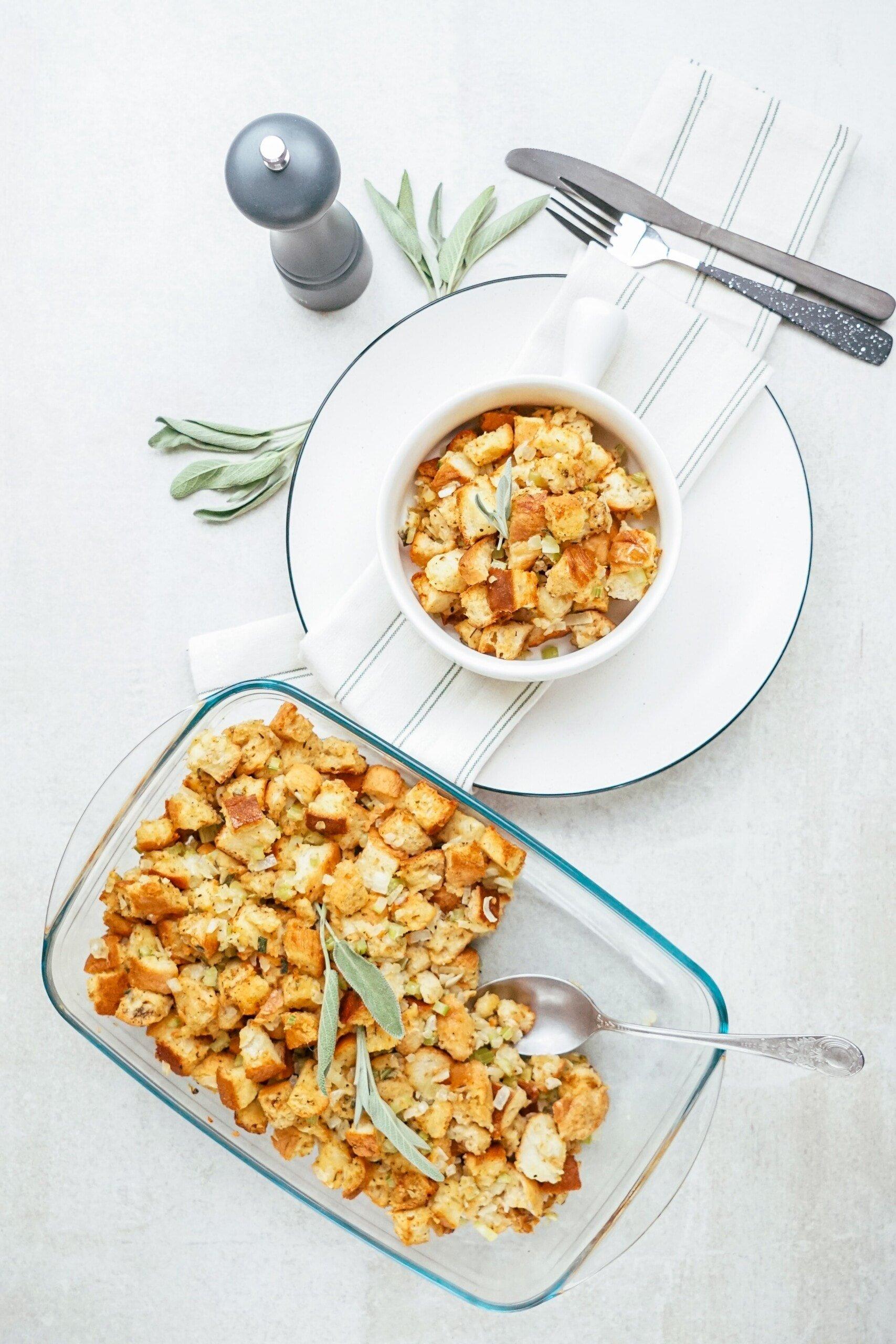 a serving of stuffing in a bowl next to the casserole pan of stuffing