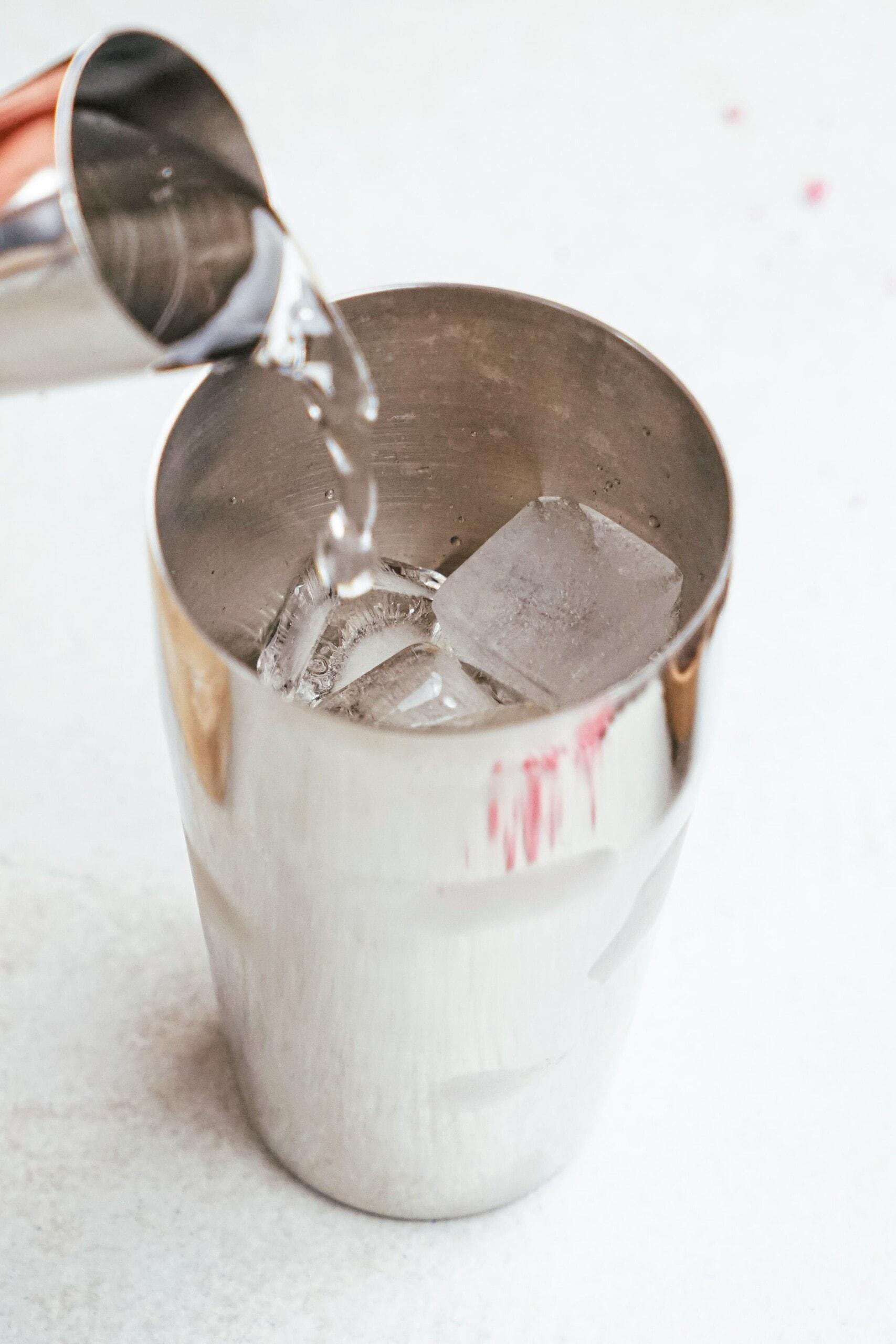 pouring in vodka to cocktail shaker and ice cubes