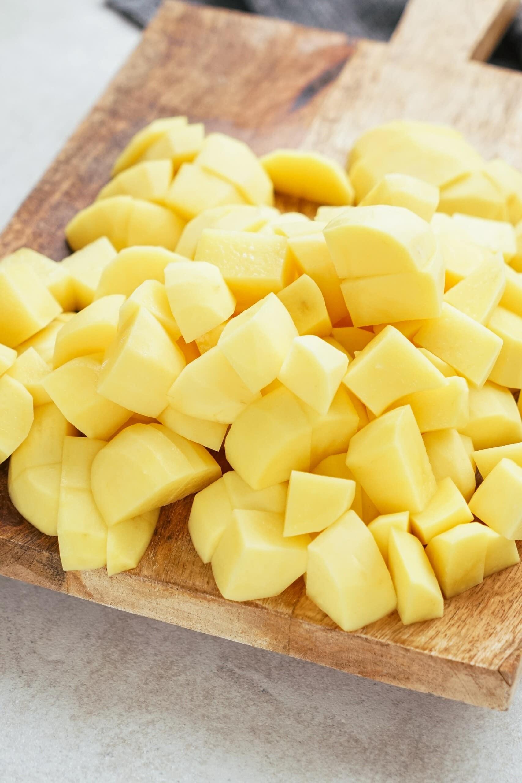 cubed potatoes in a pile on a cutting board