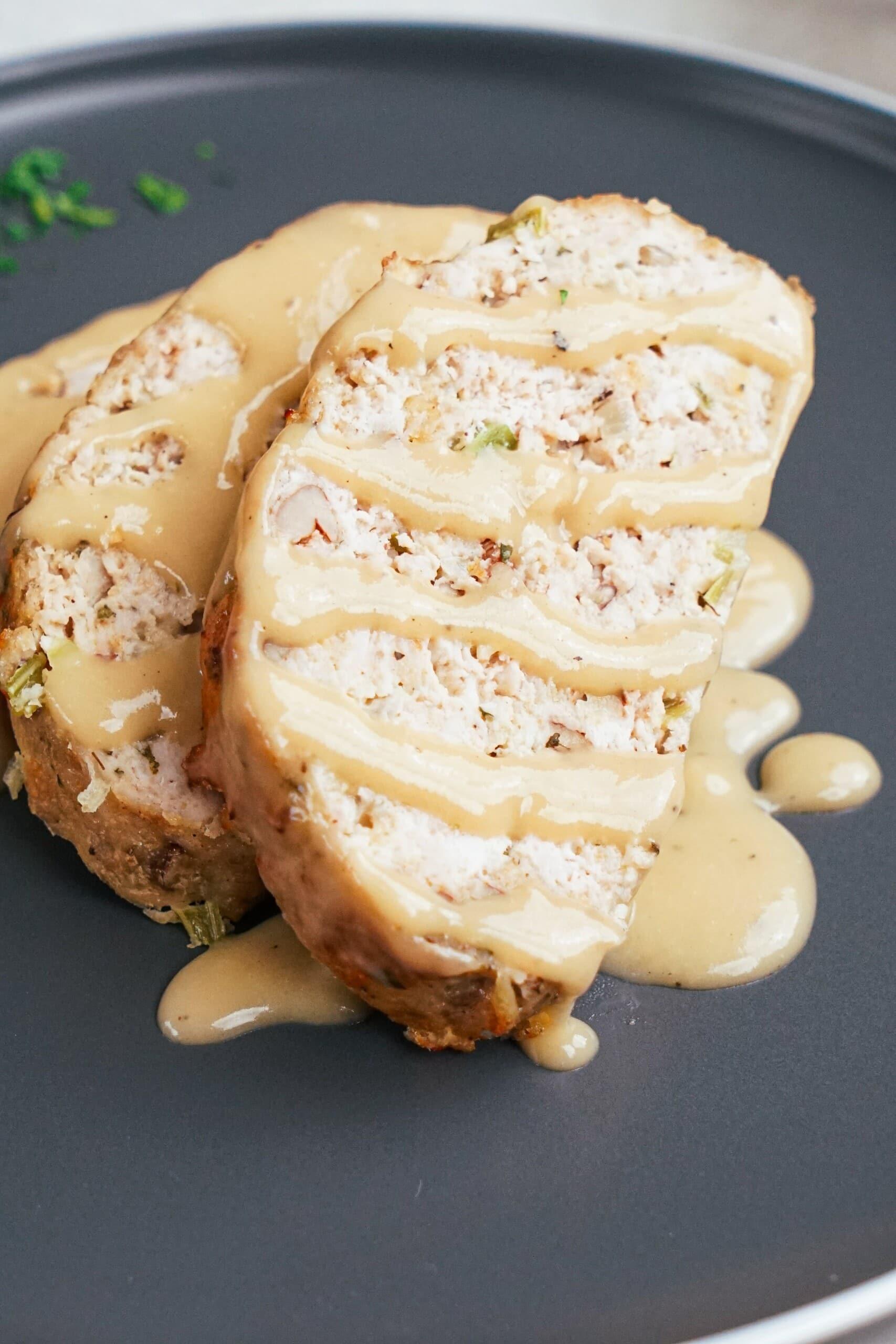 sliced meatloaf on a plate with gravy closeup