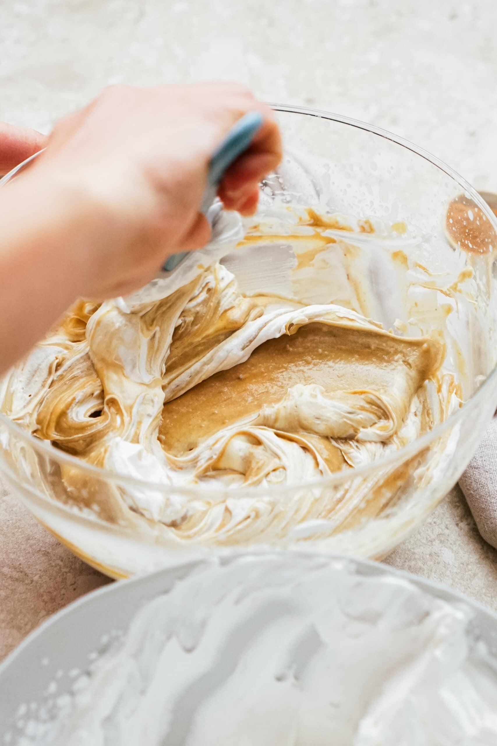 woman's hand folding in whipped cream to the gingerbread filling 