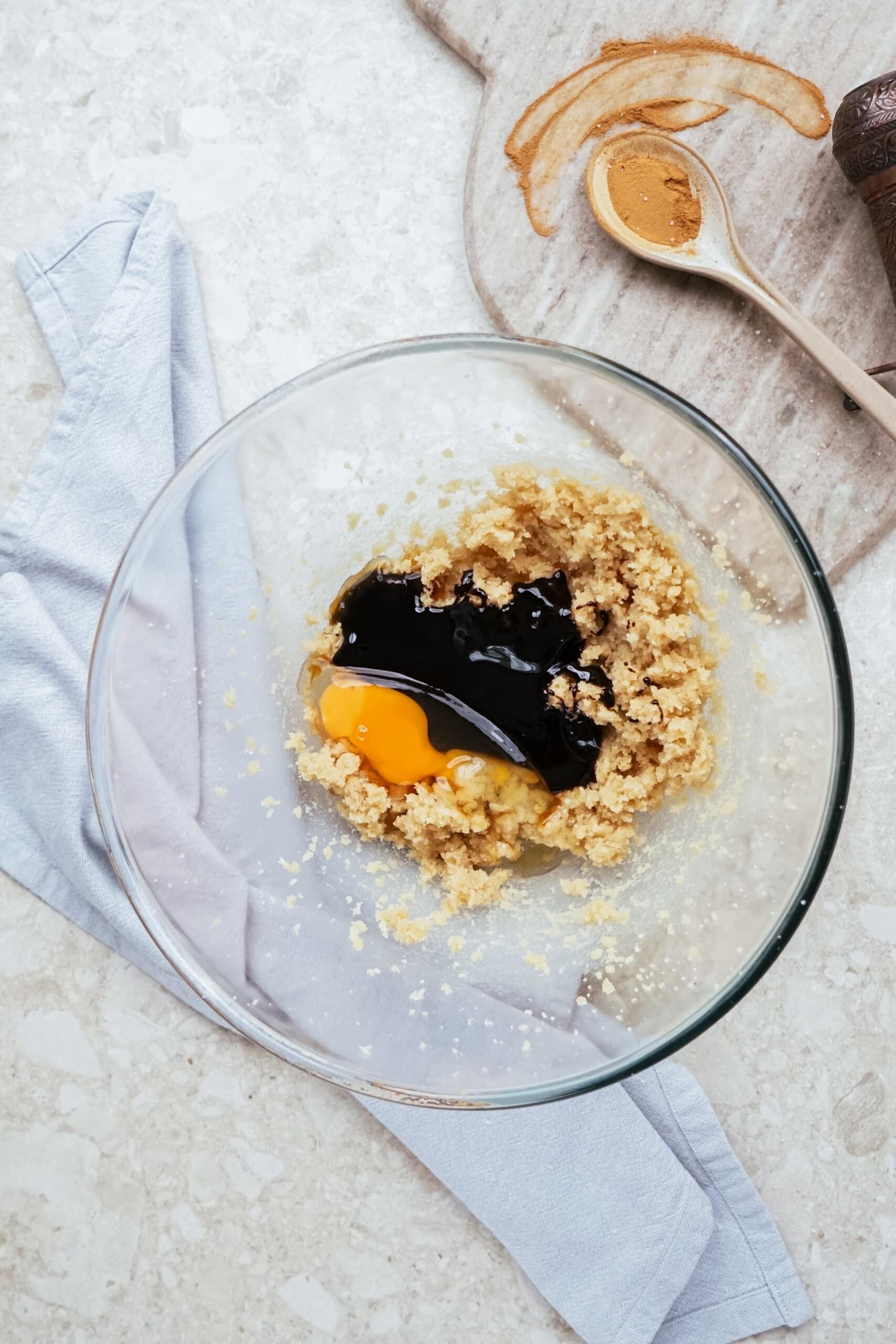 molasses and egg added to butter and sugar in a glass bowl