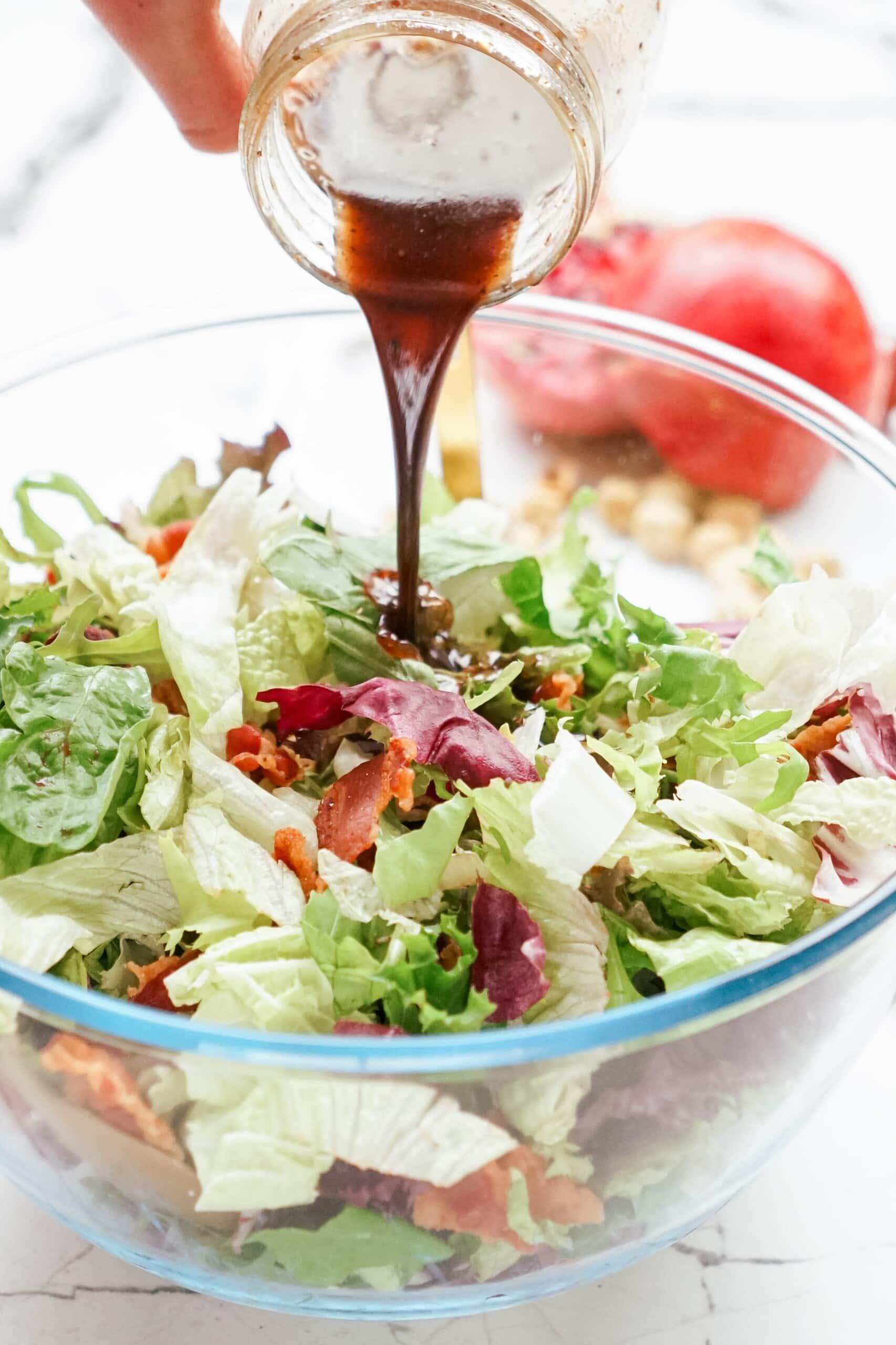 salad dressing being drizzled over salad 