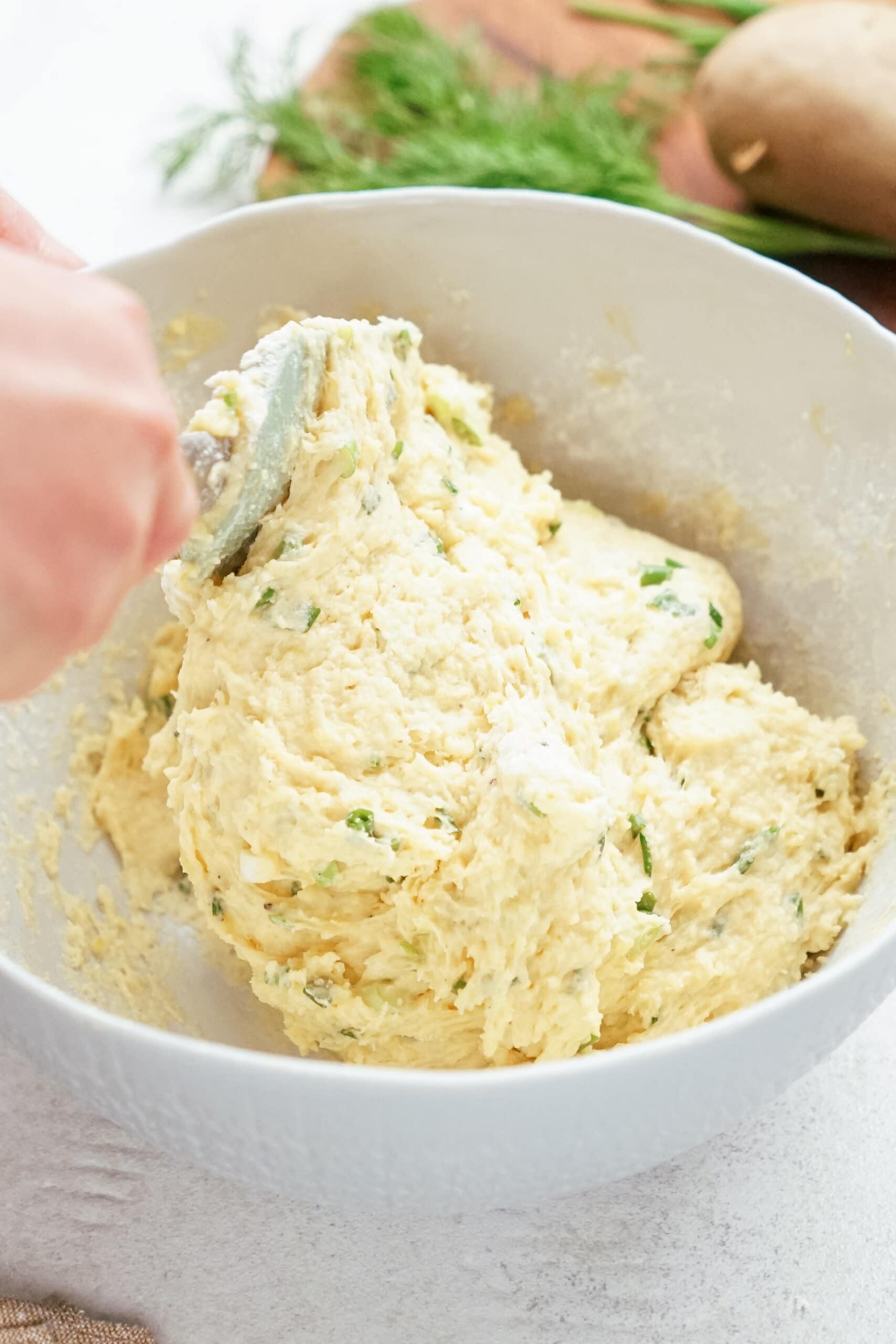 womans hand mixing potato mixture together