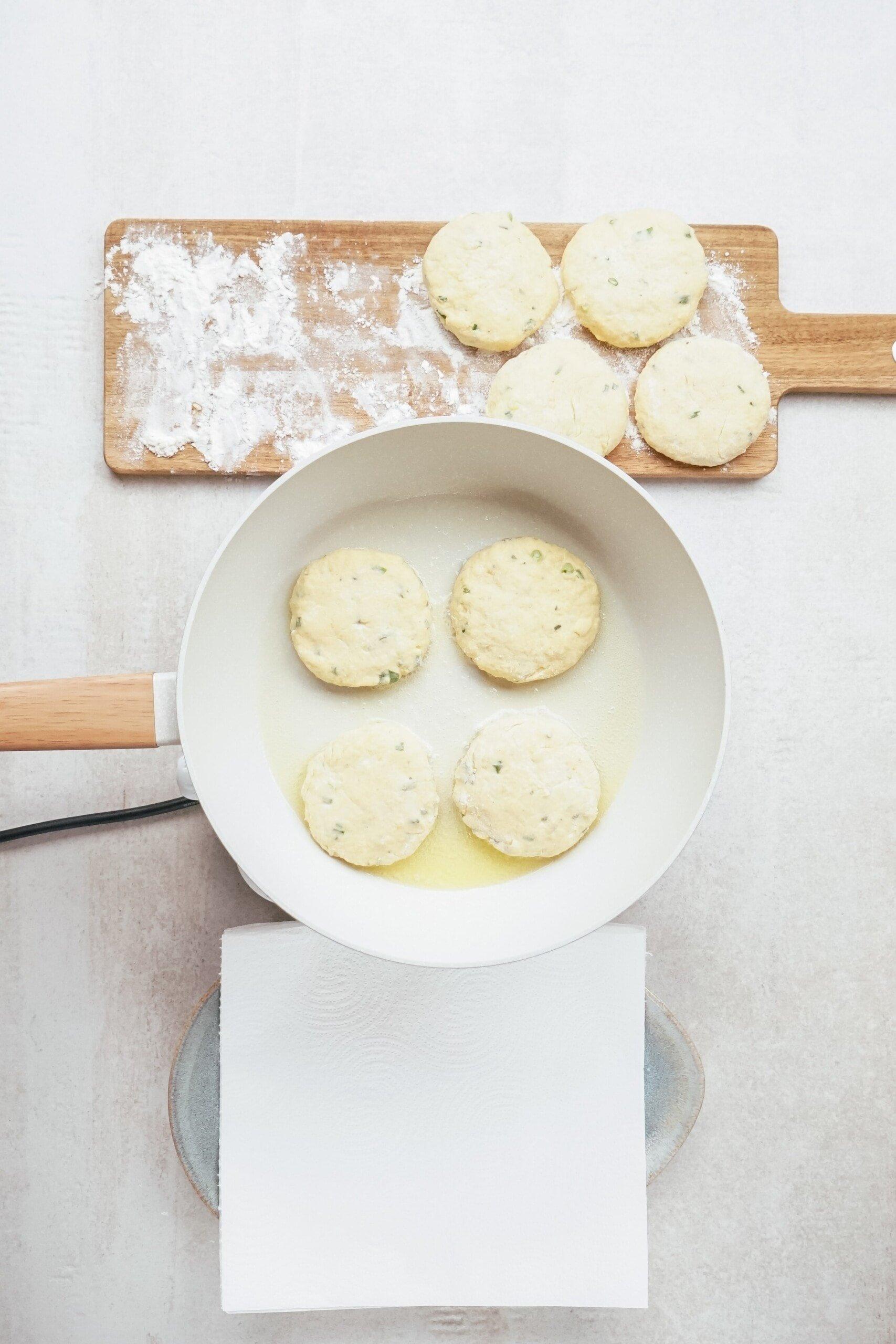  4 potato patties frying in a skillet