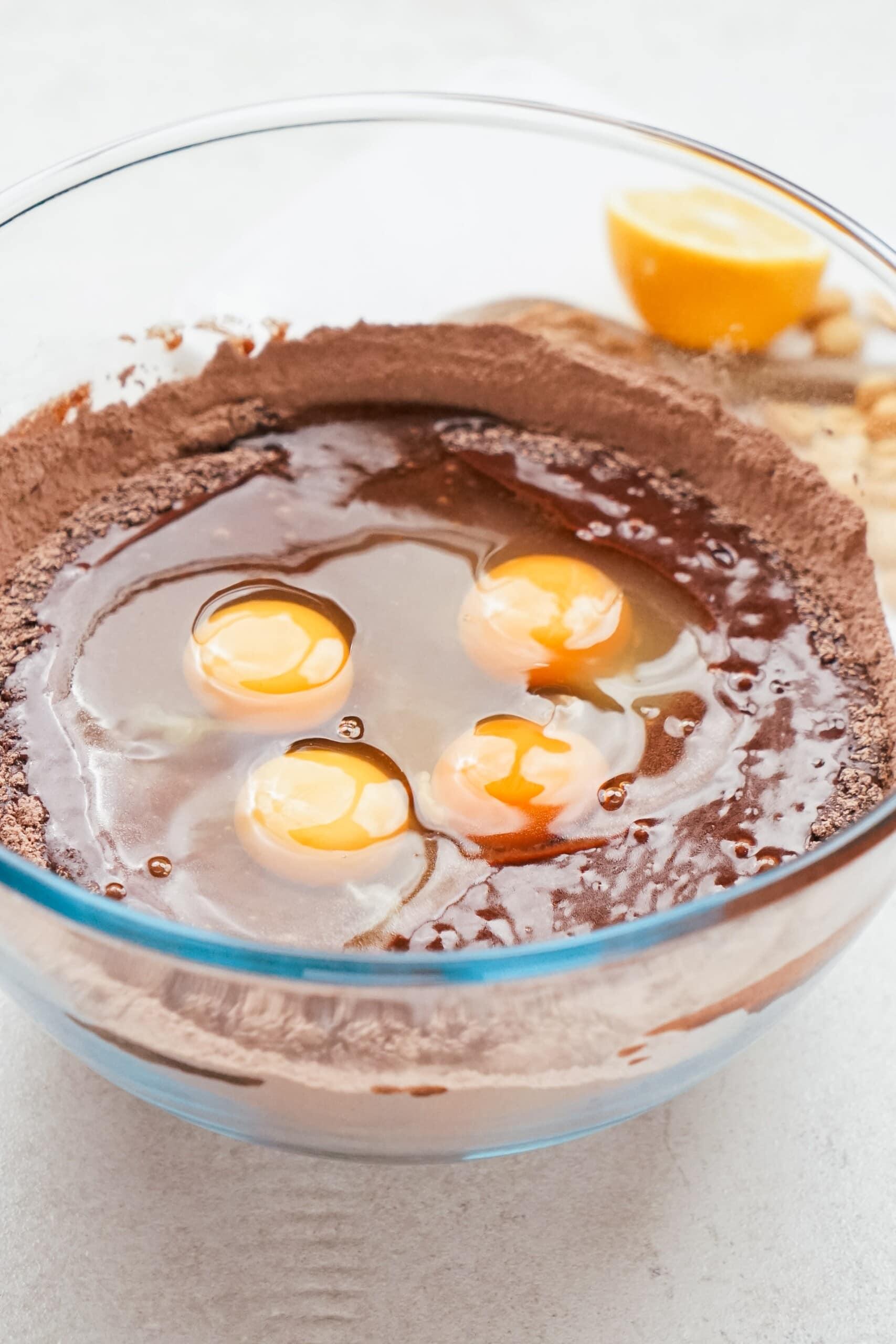 eggs added to cake batter in a glass bowl