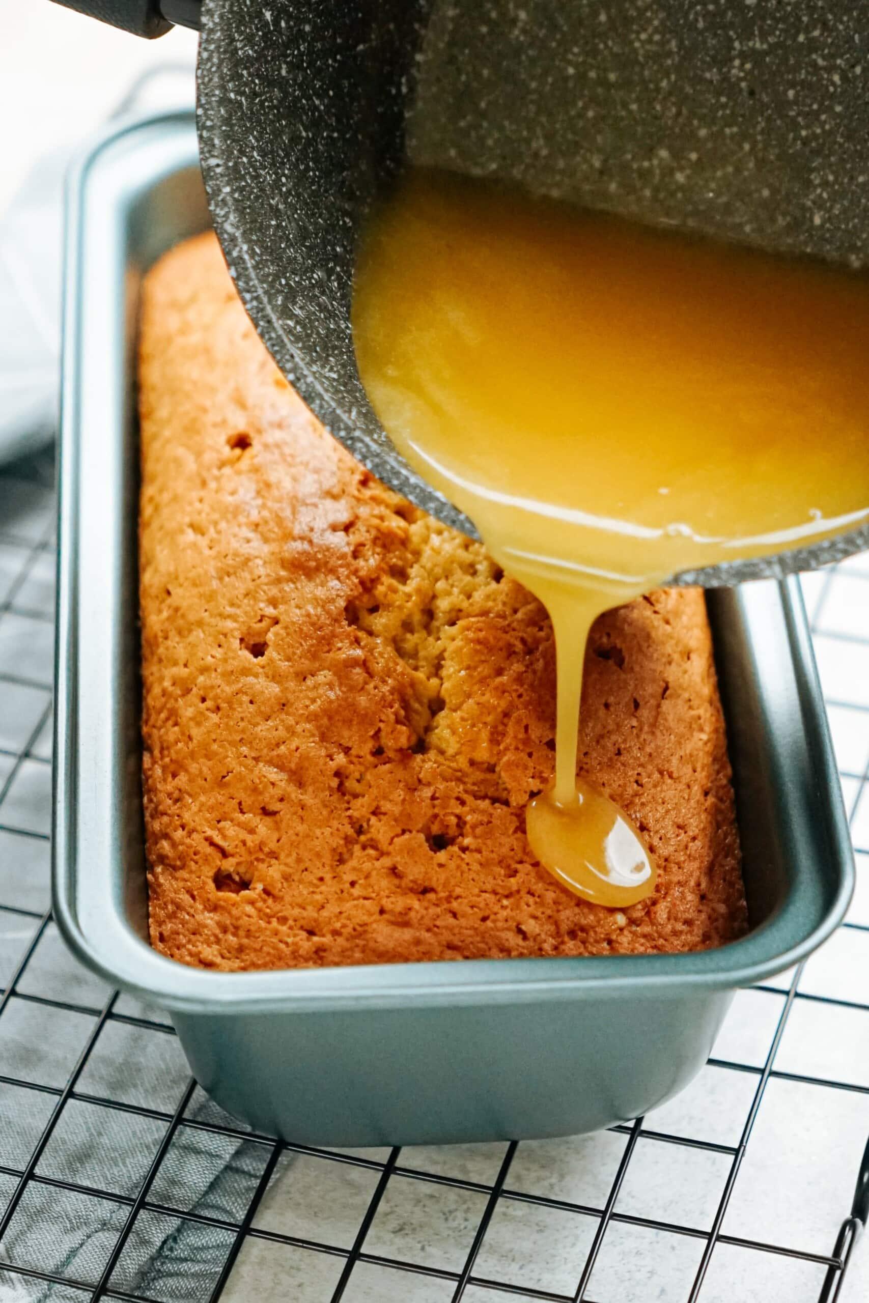 lemon glaze being poured over warm cake 