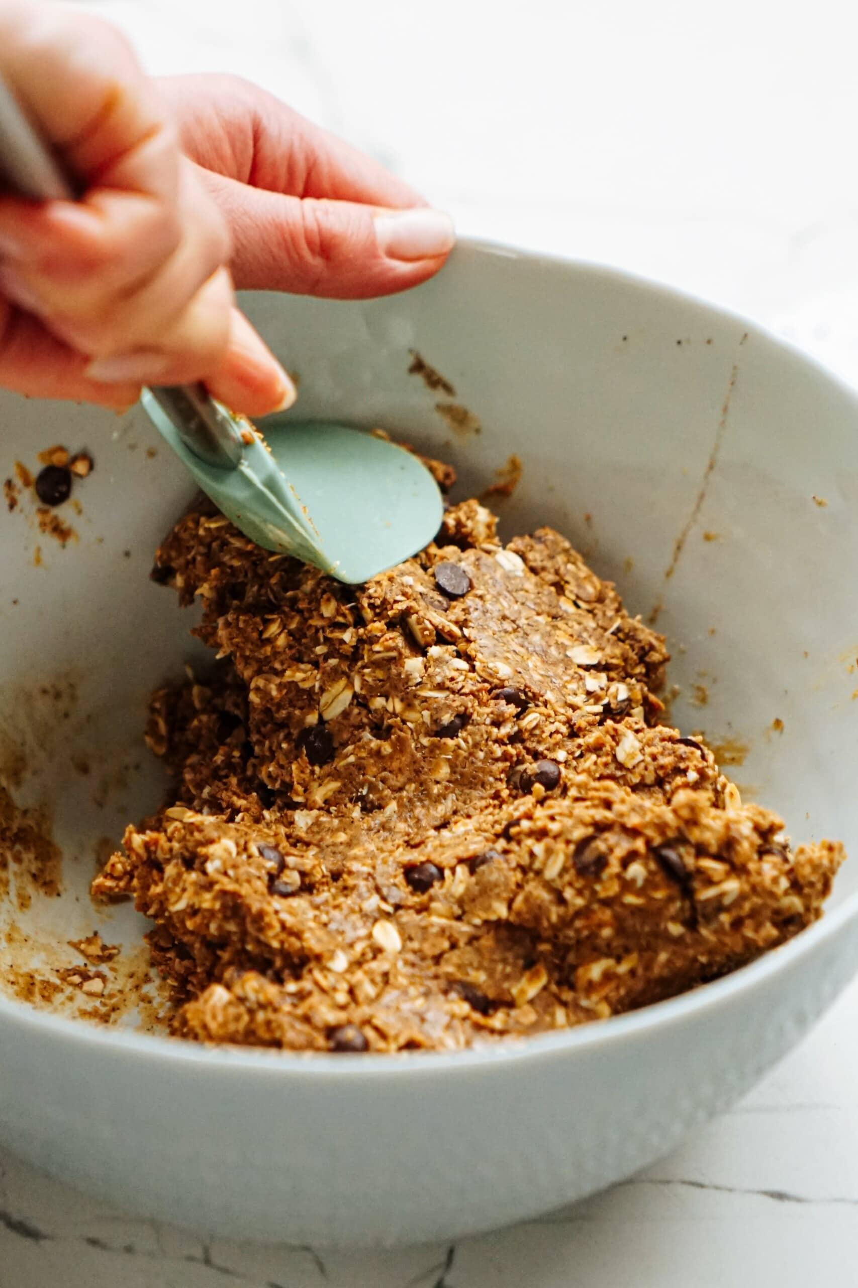 womans hand using a rubber spatula to combine ingredients