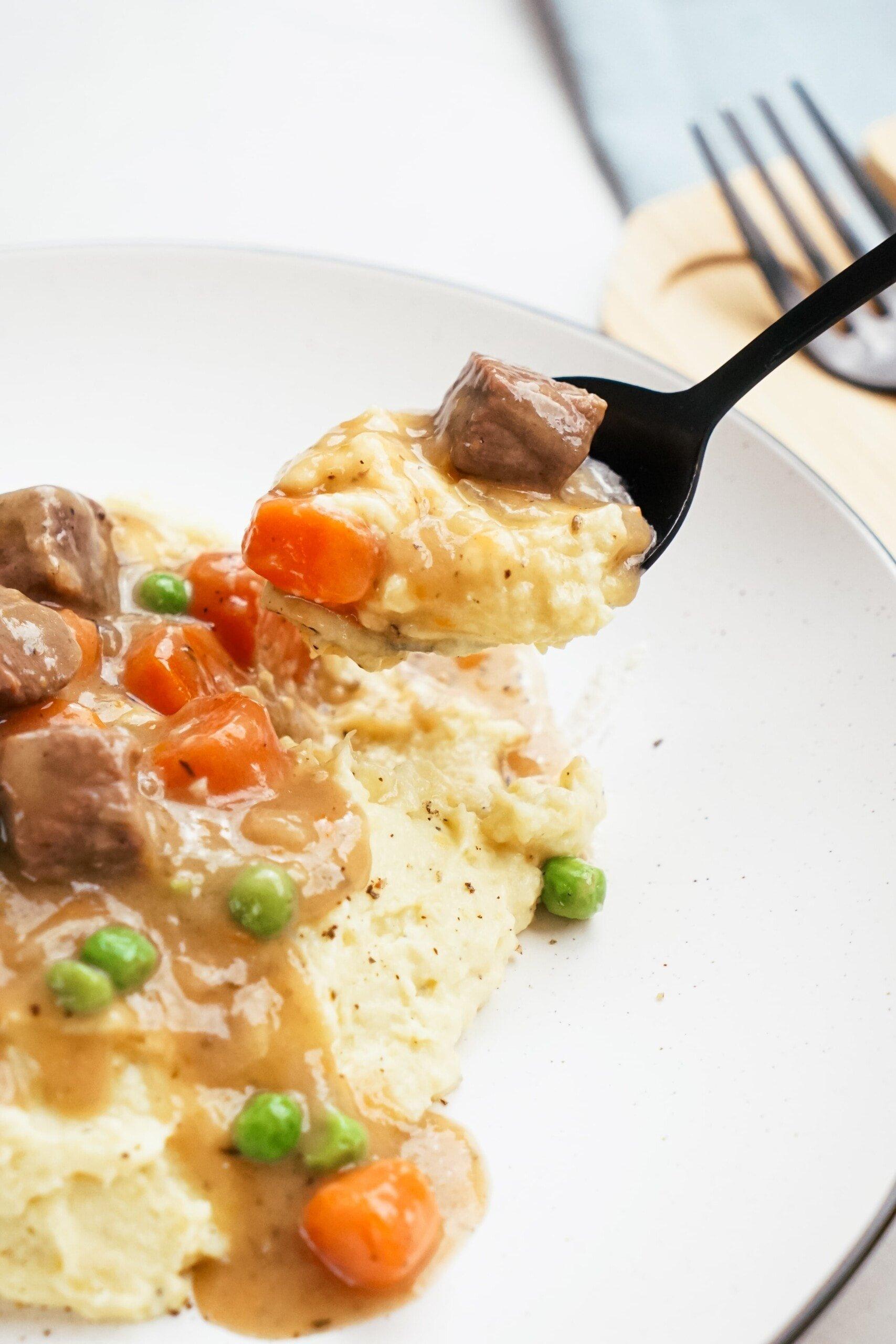 spooning out irish beef stew with mashed potatoes