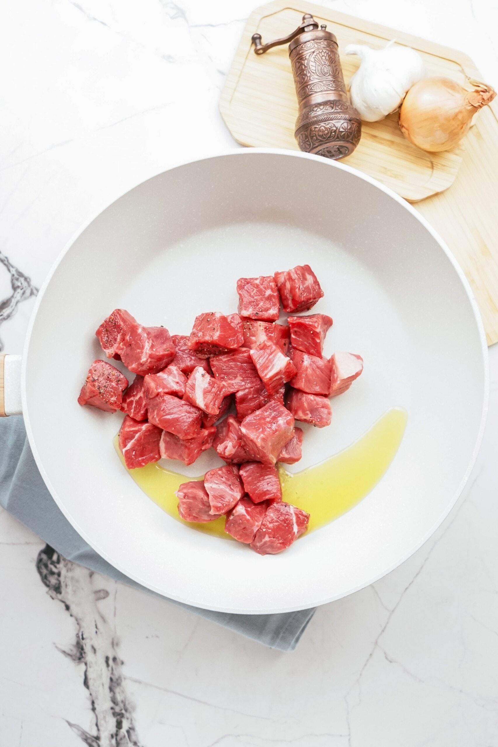 beef stew meat in pan with oil