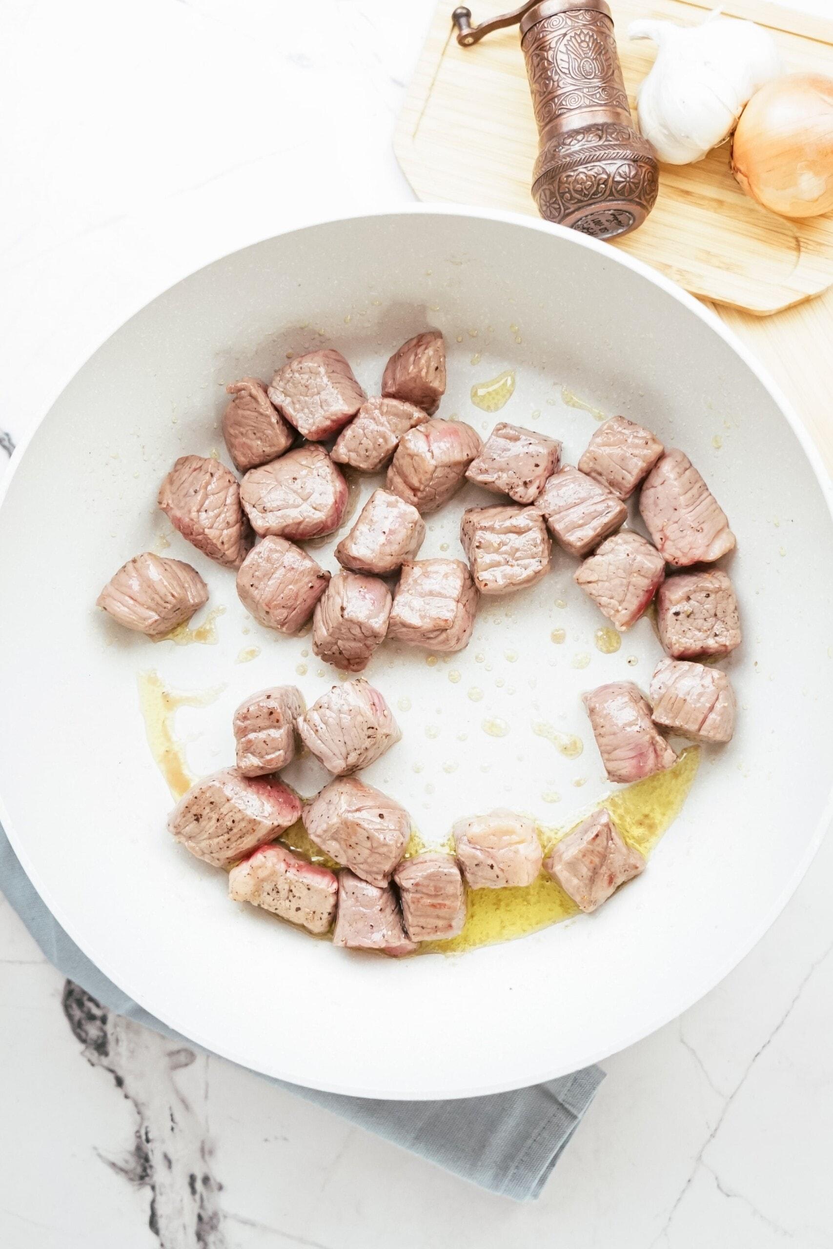 beef stew meat cooking in pan with oil