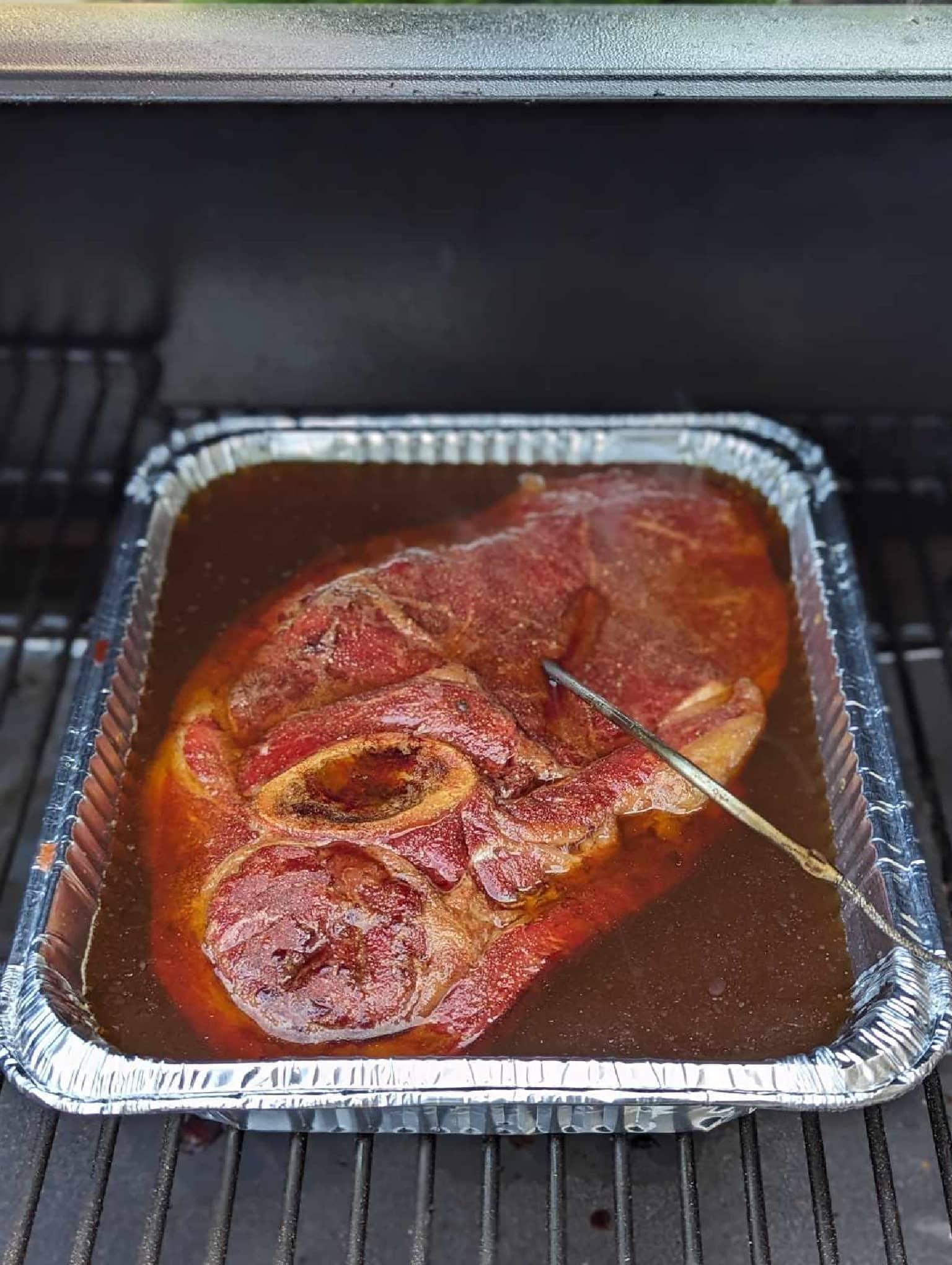 smoked arm roast in aluminum pan with beef broth and temp probe inserted