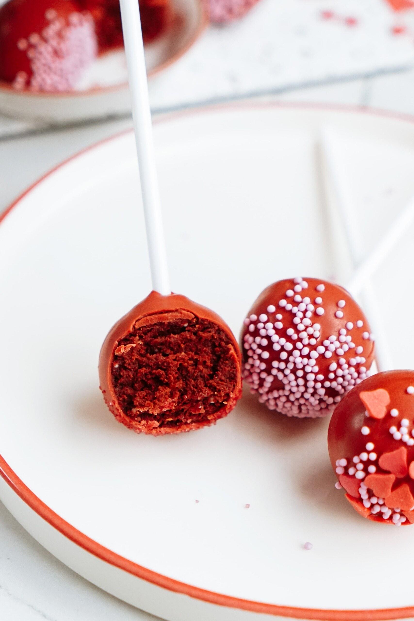 cake pops on a plate, one of them showing the inside of the cake pop