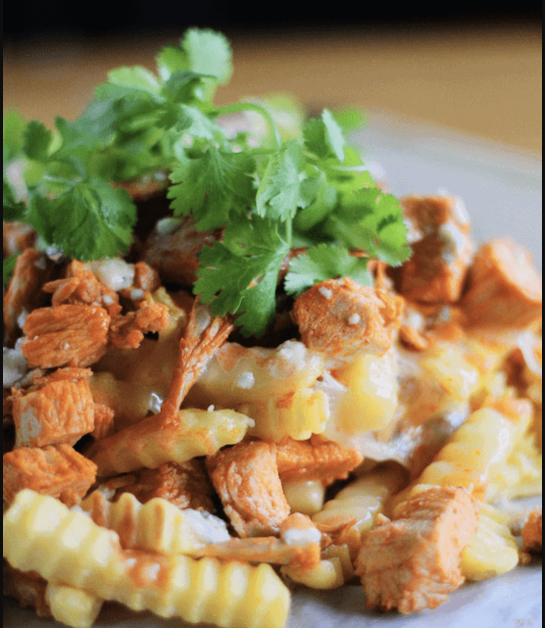 buffalo chicken dip fries piled on plate with cilantro on top