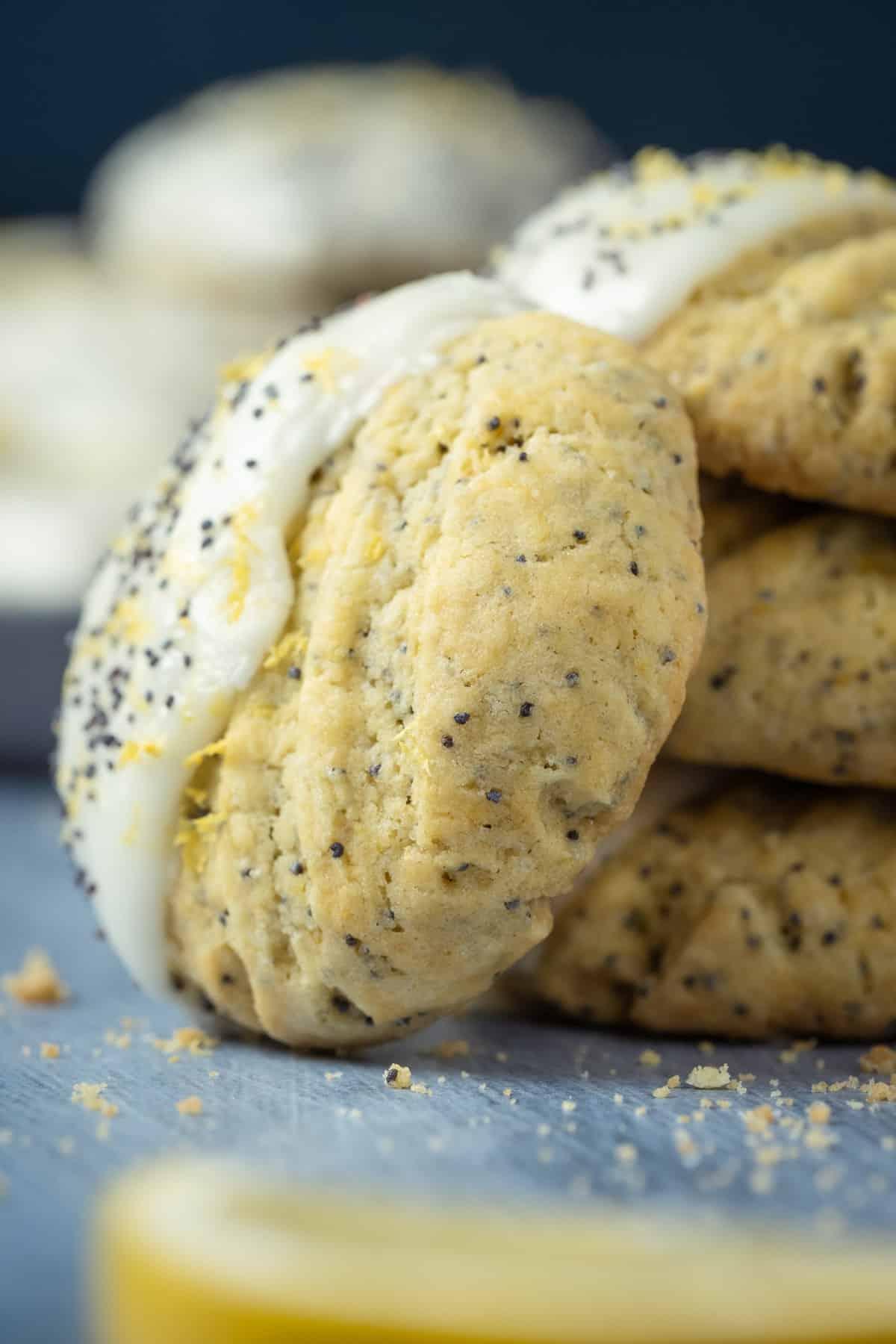 Vegan lemon poppy seed cookies stacked with one cookie balancing on its side.
