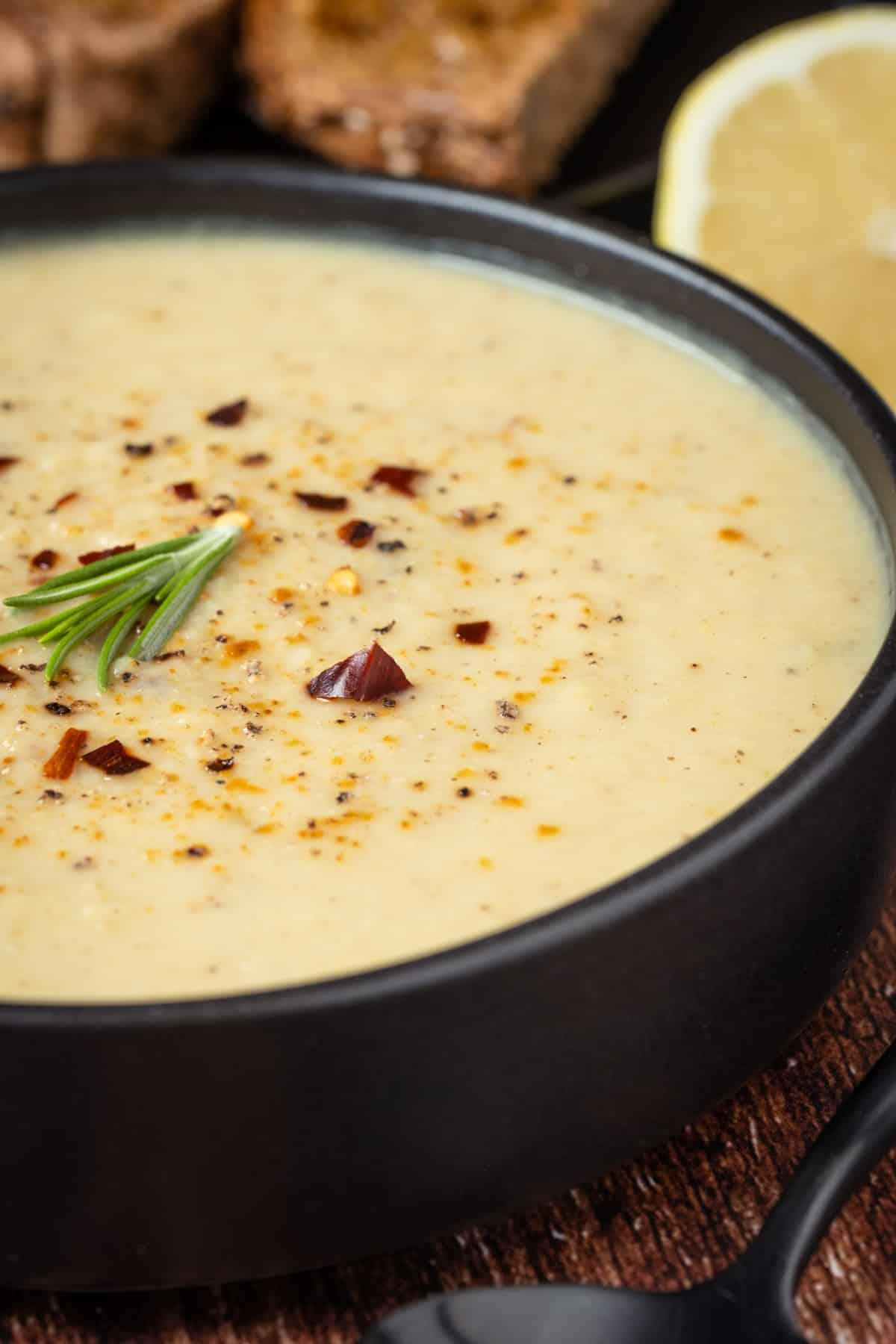 A close up photo of Vegan Roasted Cauliflower Soup in a black bowl